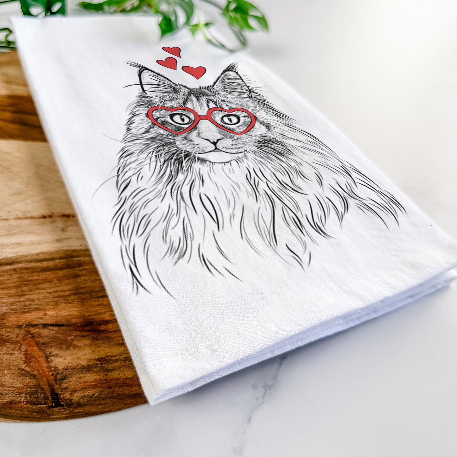 Hand-drawn sketch of Kiki the Maine Coon Cat wearing heart-shaped glasses on a tea towel