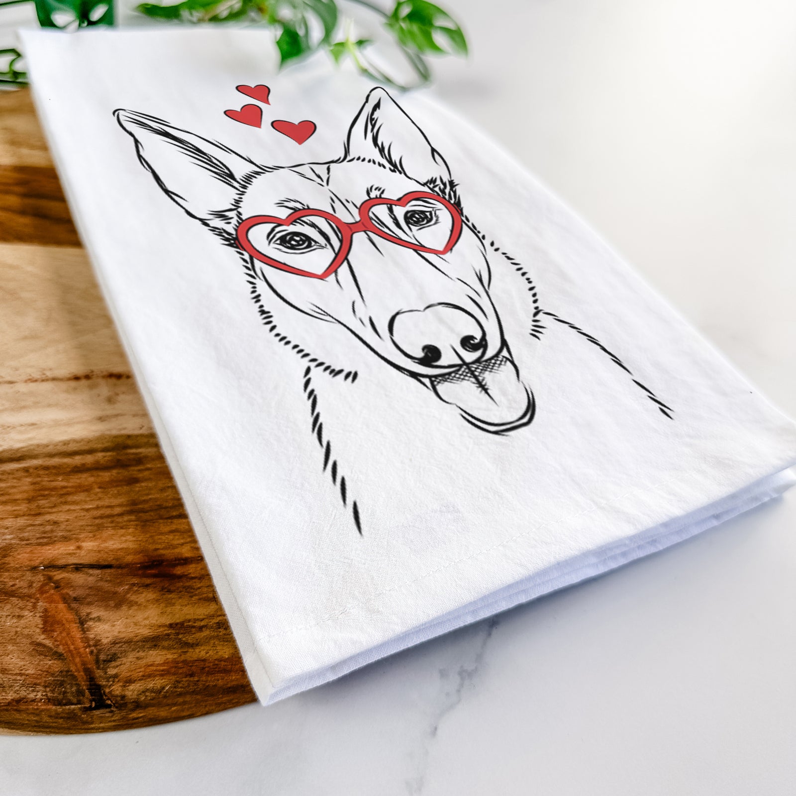 Hand-drawn sketch of Lyric the Belgian Malinois wearing heart-shaped glasses on a tea towel