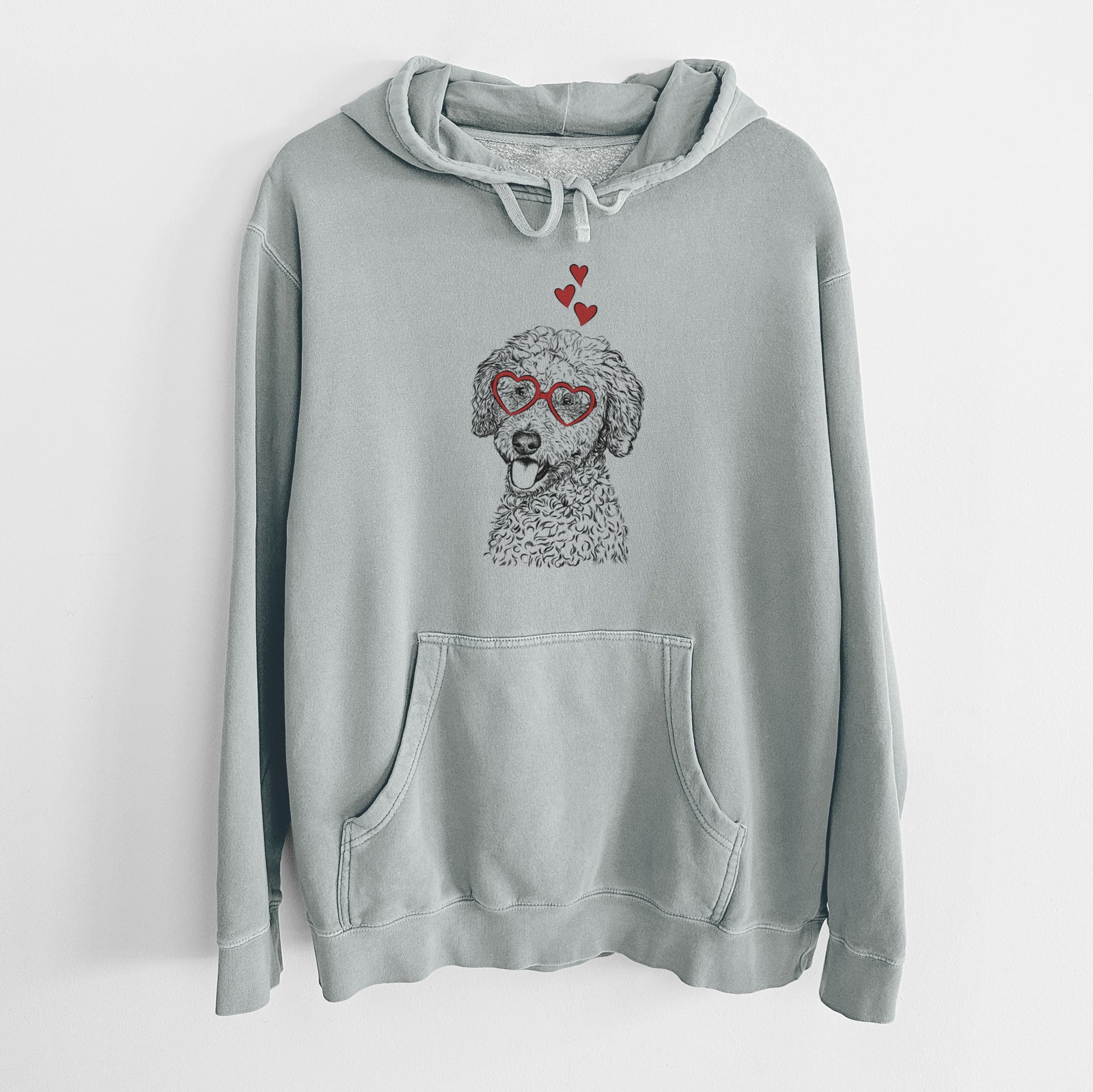 Hand-drawn sketch of Marlow the Goldendoodle wearing heart-shaped glasses on a Sage Unisex pigment dyed hoodie