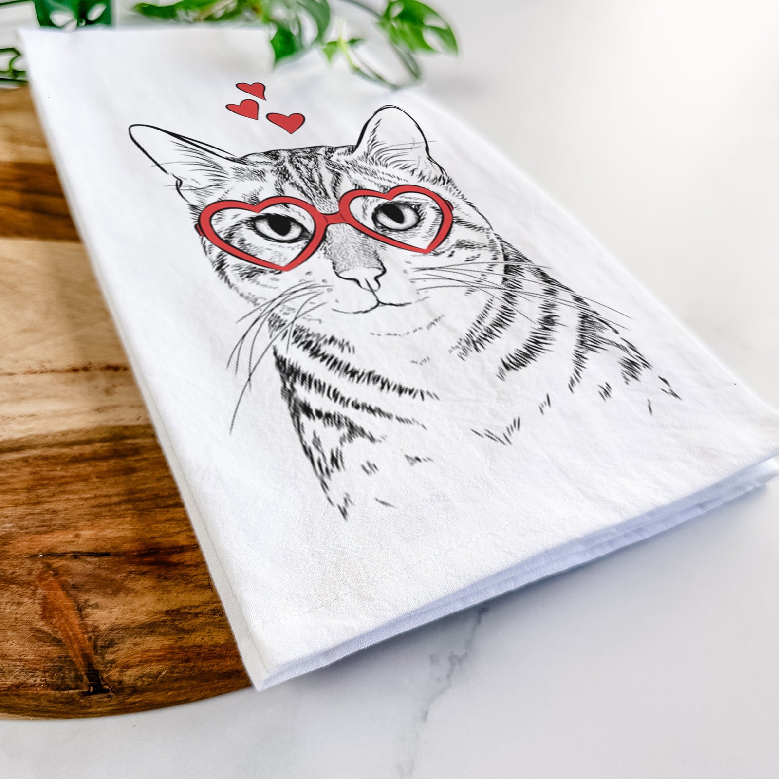 Hand-drawn sketch of Nell the Tabby Cat wearing heart-shaped glasses on a tea towel