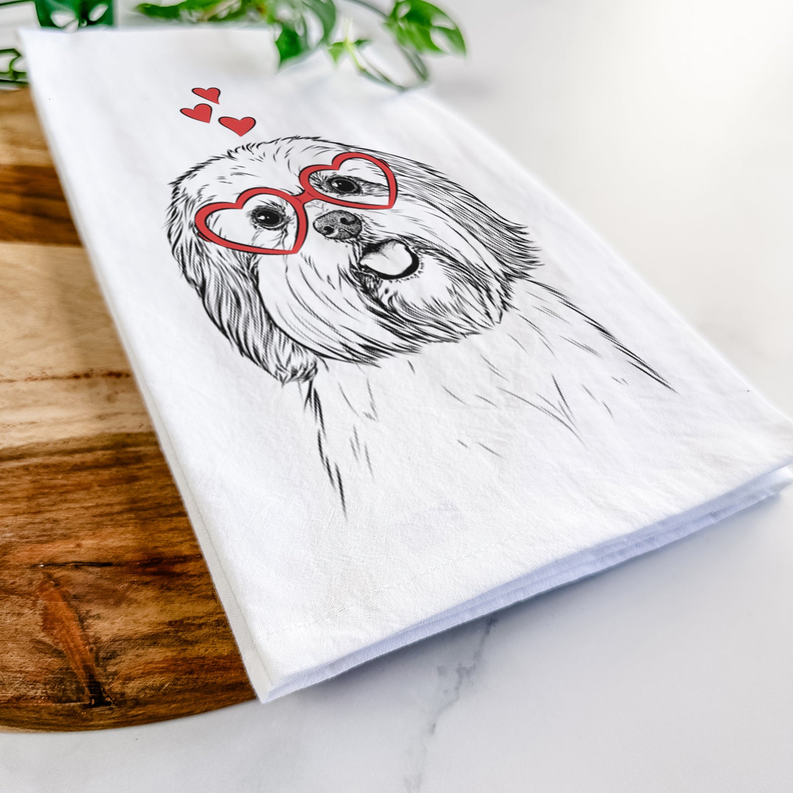 Hand-drawn sketch of Nikka the Lowchen wearing heart-shaped glasses on a tea towel