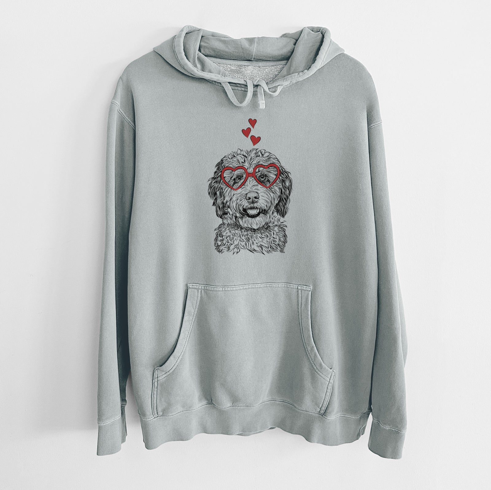 Hand-drawn sketch of Palmer the Aussiedoodle wearing heart-shaped glasses on a Sage Unisex pigment dyed hoodie