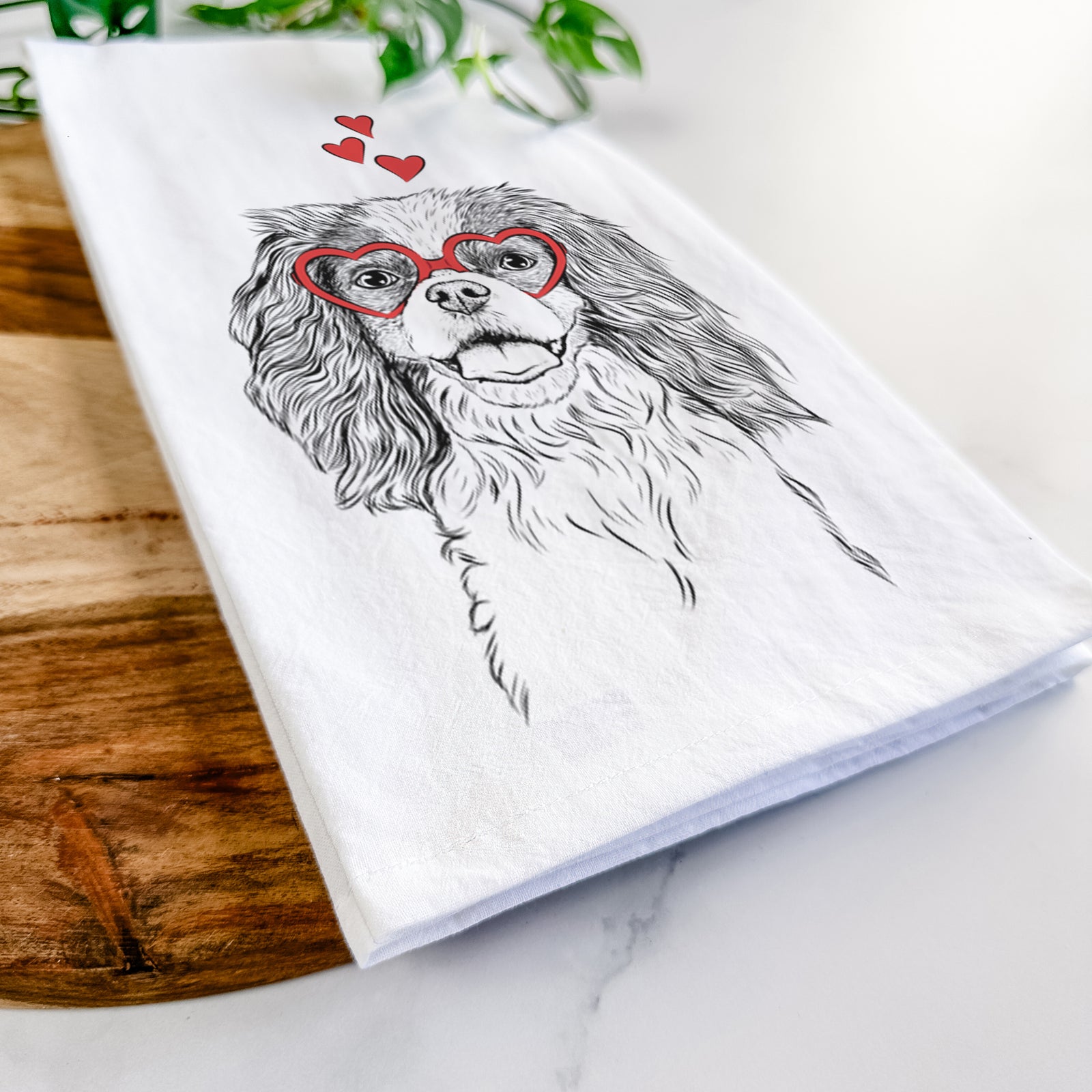 Hand-drawn sketch of Poppy the Cavalier King Charles Spaniel wearing heart-shaped glasses on a tea towel
