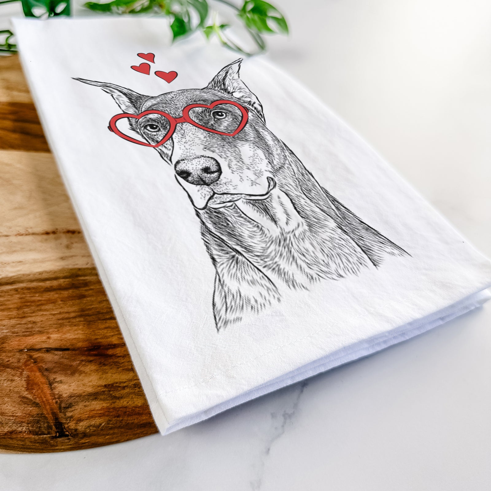 Hand-drawn sketch of RJ the Doberman Pinscher wearing heart-shaped glasses on a tea towel