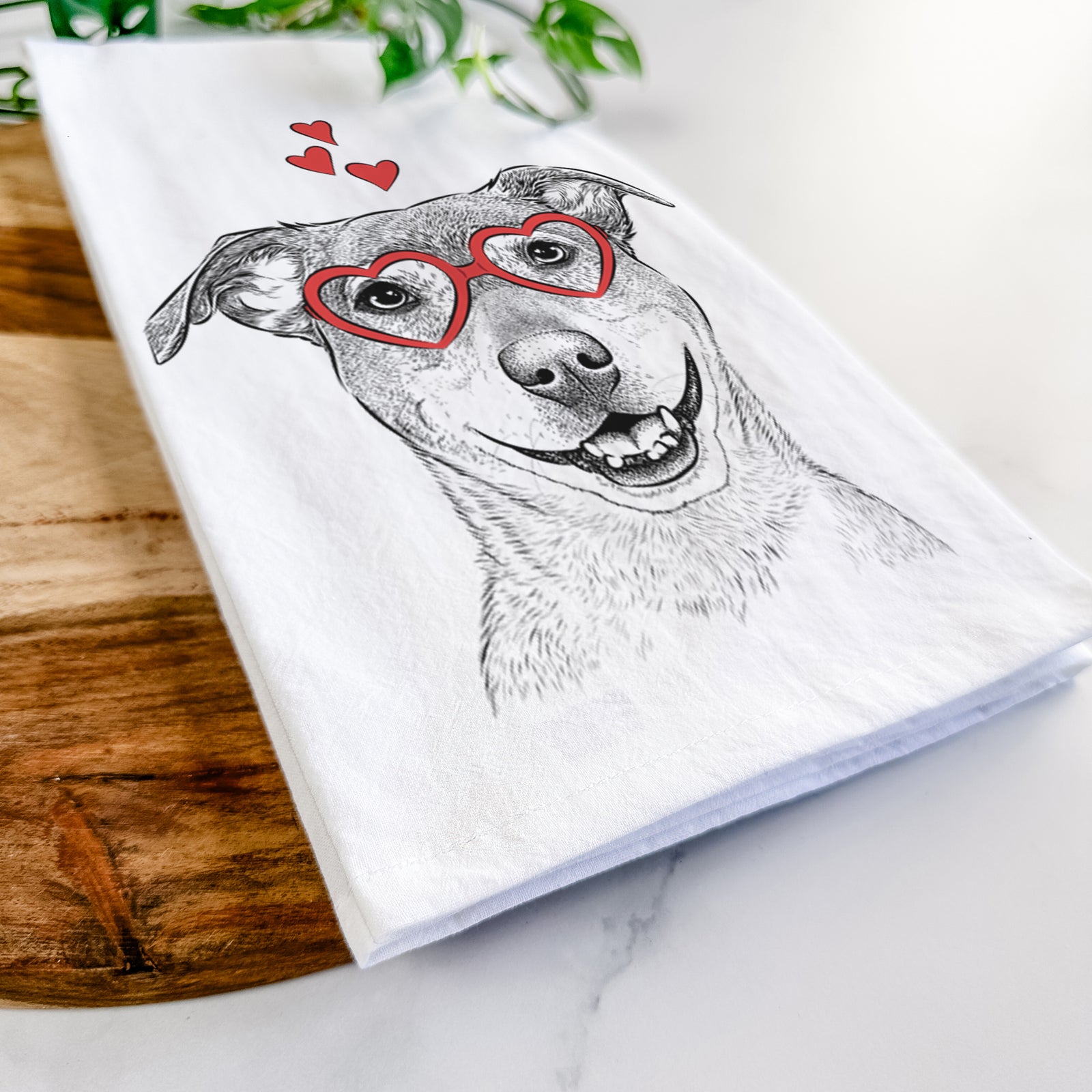 Hand-drawn sketch of Reese the Mountain Cur wearing heart-shaped glasses on a tea towel
