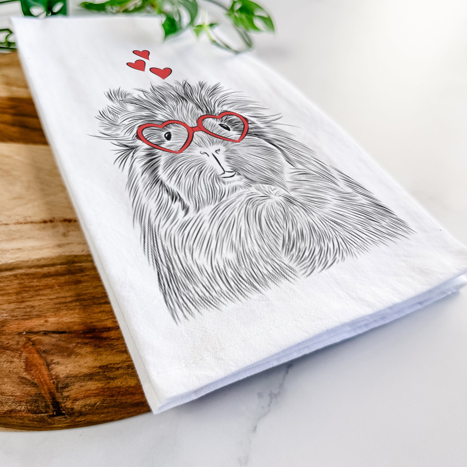 Hand-drawn sketch of Rhino the Guinea Pig wearing heart-shaped glasses on a tea towel