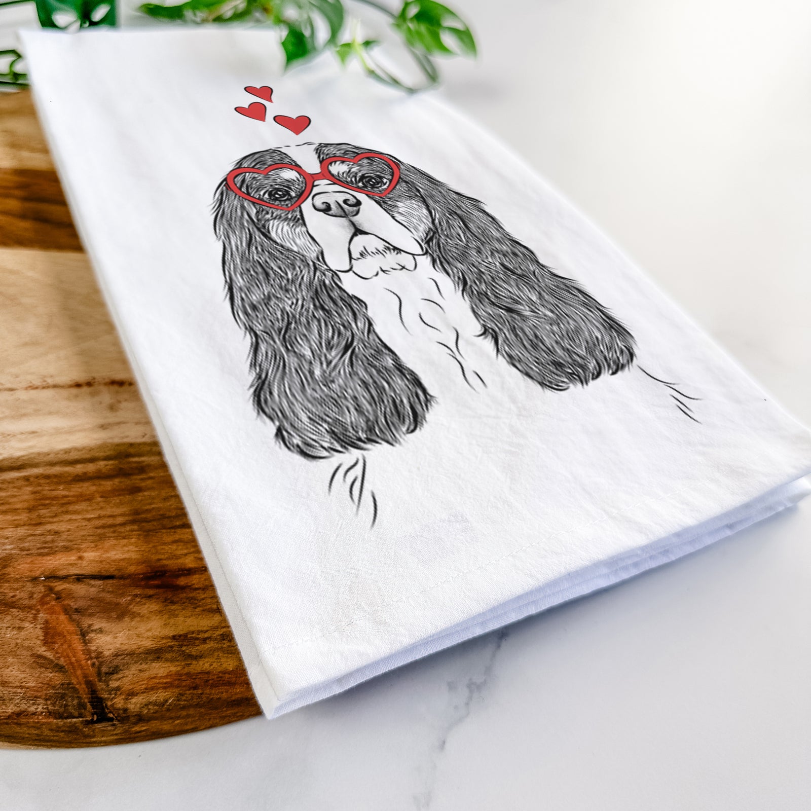 Hand-drawn sketch of Sebastian the Cavalier King Charles Spaniel wearing heart-shaped glasses on a tea towel