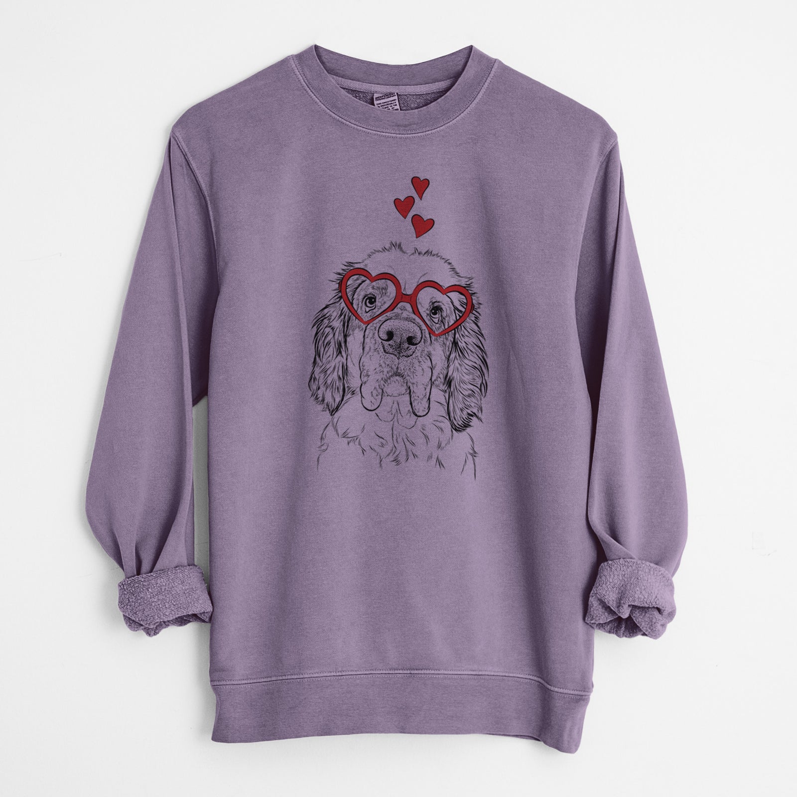 Hand-drawn sketch of Sully the Clumber Spaniel wearing heart-shaped glasses on a Plum Unisex pigment dyed crew sweatshirt