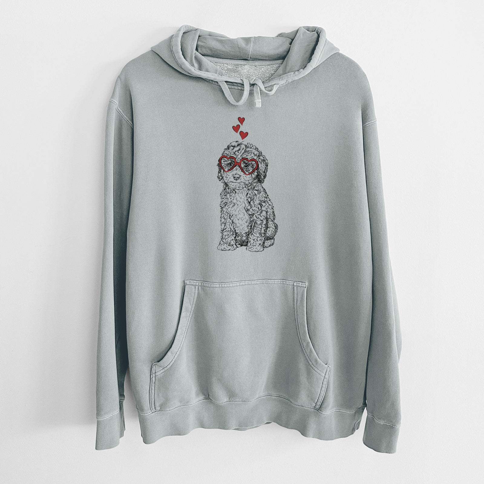 Hand-drawn sketch of Sweet Tea the Mini Doodle wearing heart-shaped glasses on a Sage Unisex pigment dyed hoodie