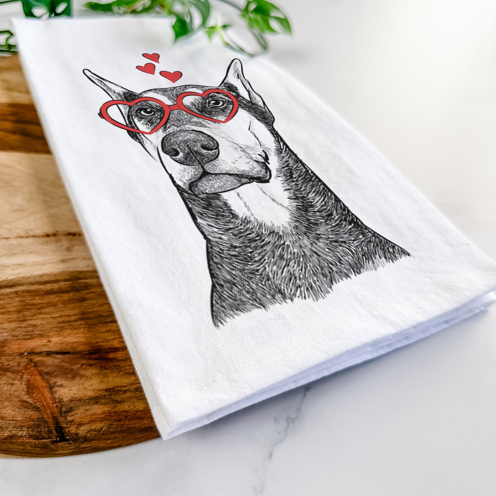 Hand-drawn sketch of Zeus the Doberman Pinscher wearing heart-shaped glasses on a tea towel