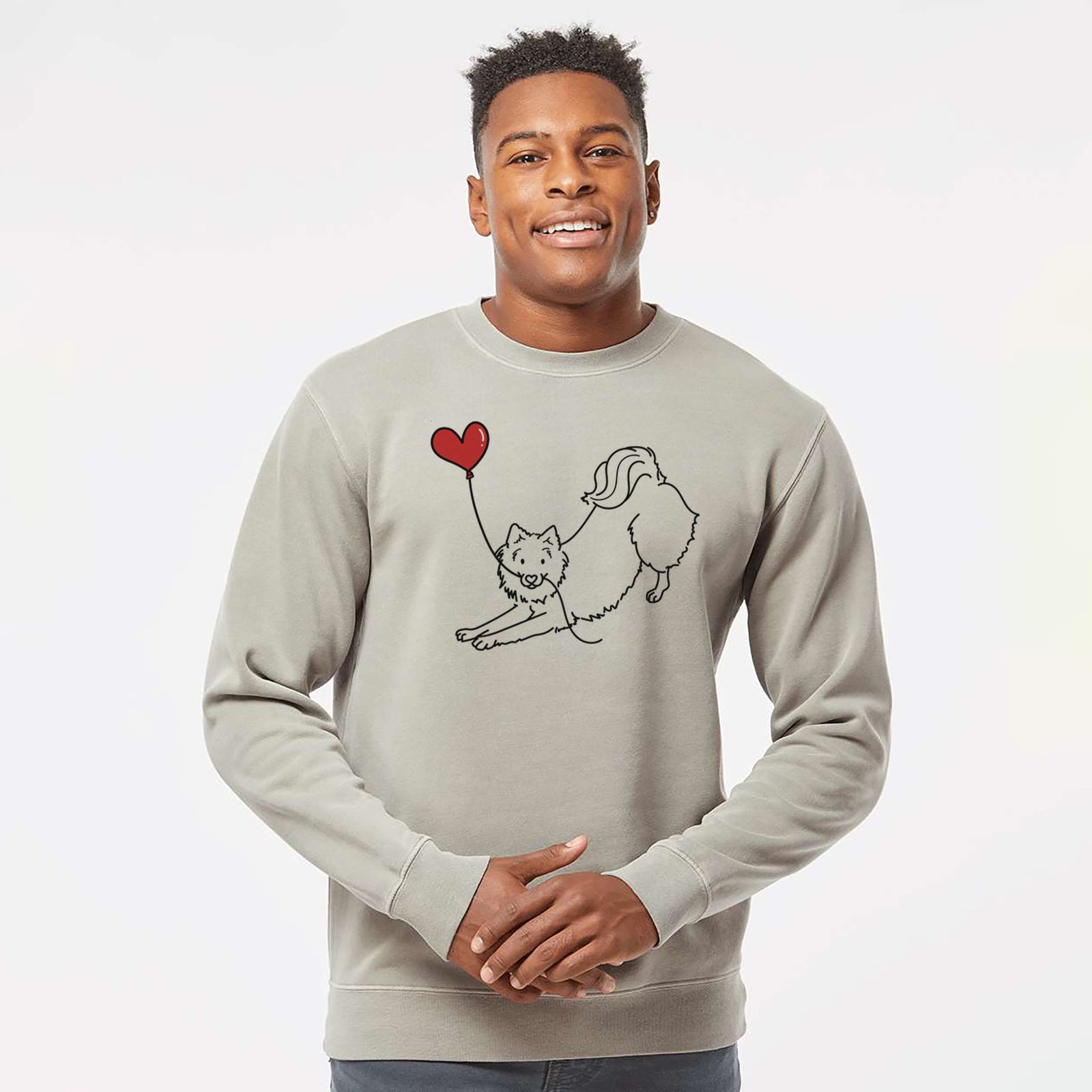 Minimalist line drawing of an American Eskimo Heart String holding a heart balloon on a Cement Unisex pigment dyed crew sweatshirt