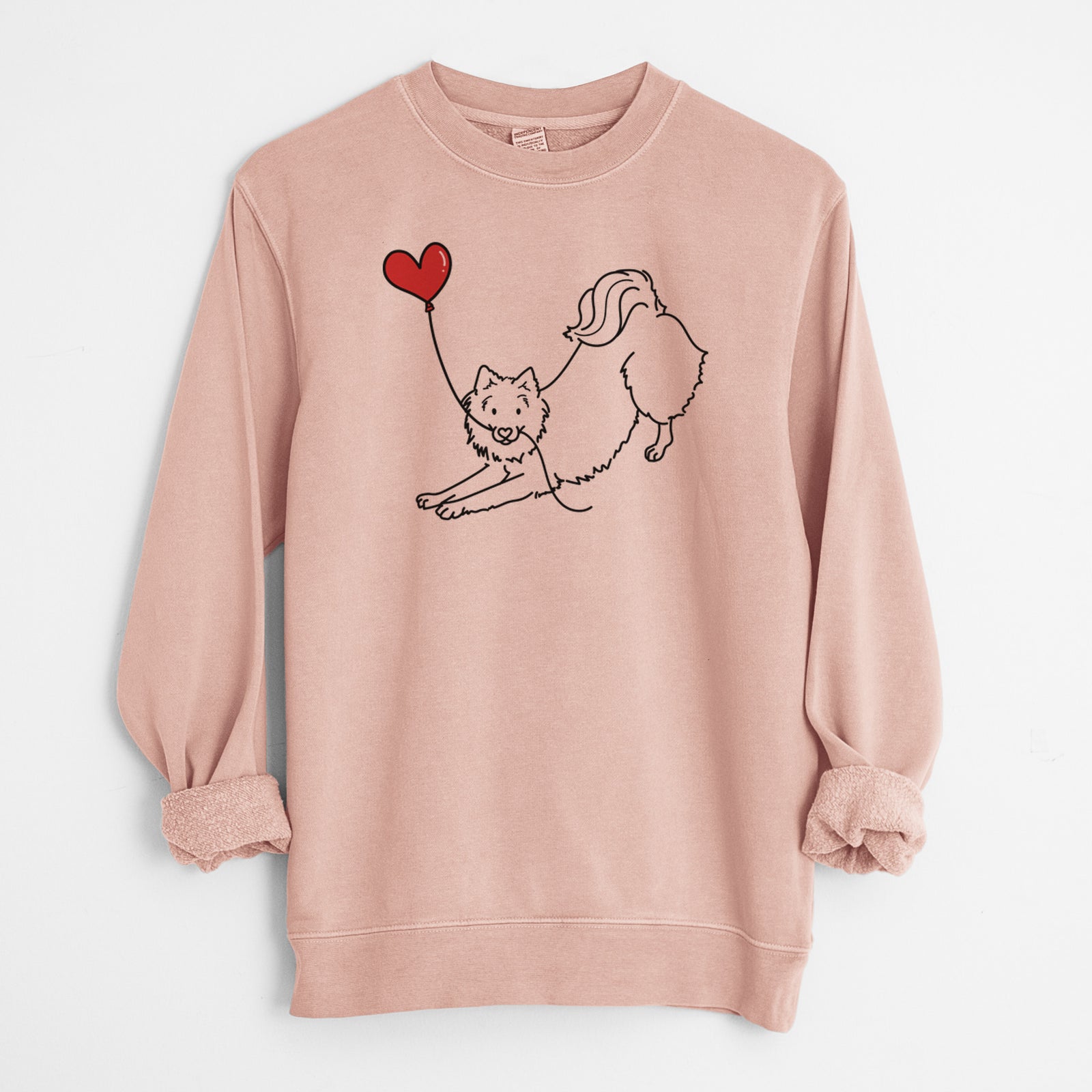 Minimalist line drawing of an American Eskimo Heart String holding a heart balloon on a Dusty Pink Unisex pigment dyed crew sweatshirt