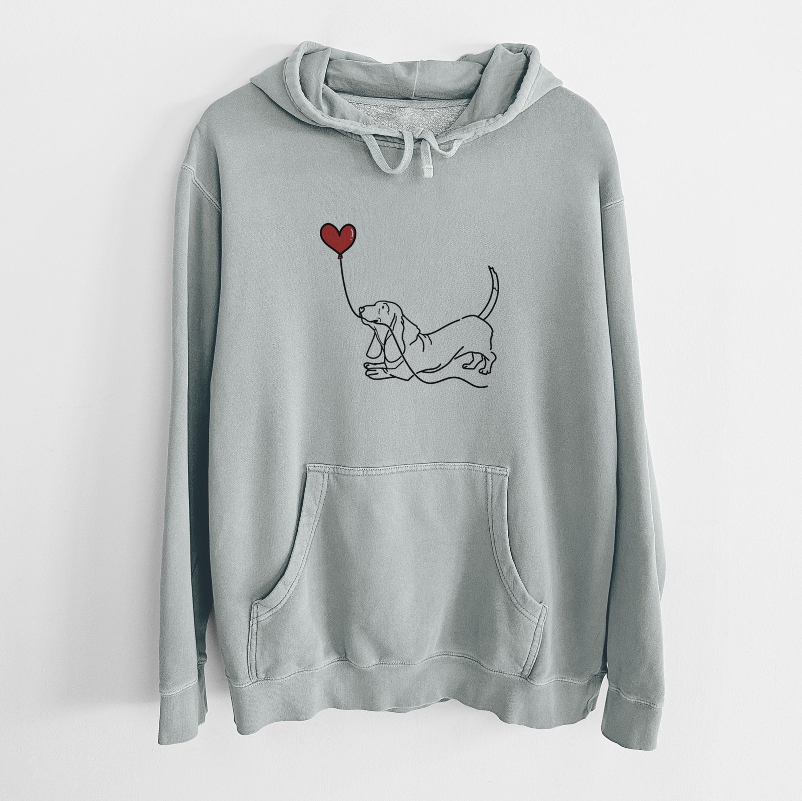 Minimalist line drawing of a Basset Hound Heart String holding a heart balloon on a Sage Unisex pigment dyed hoodie