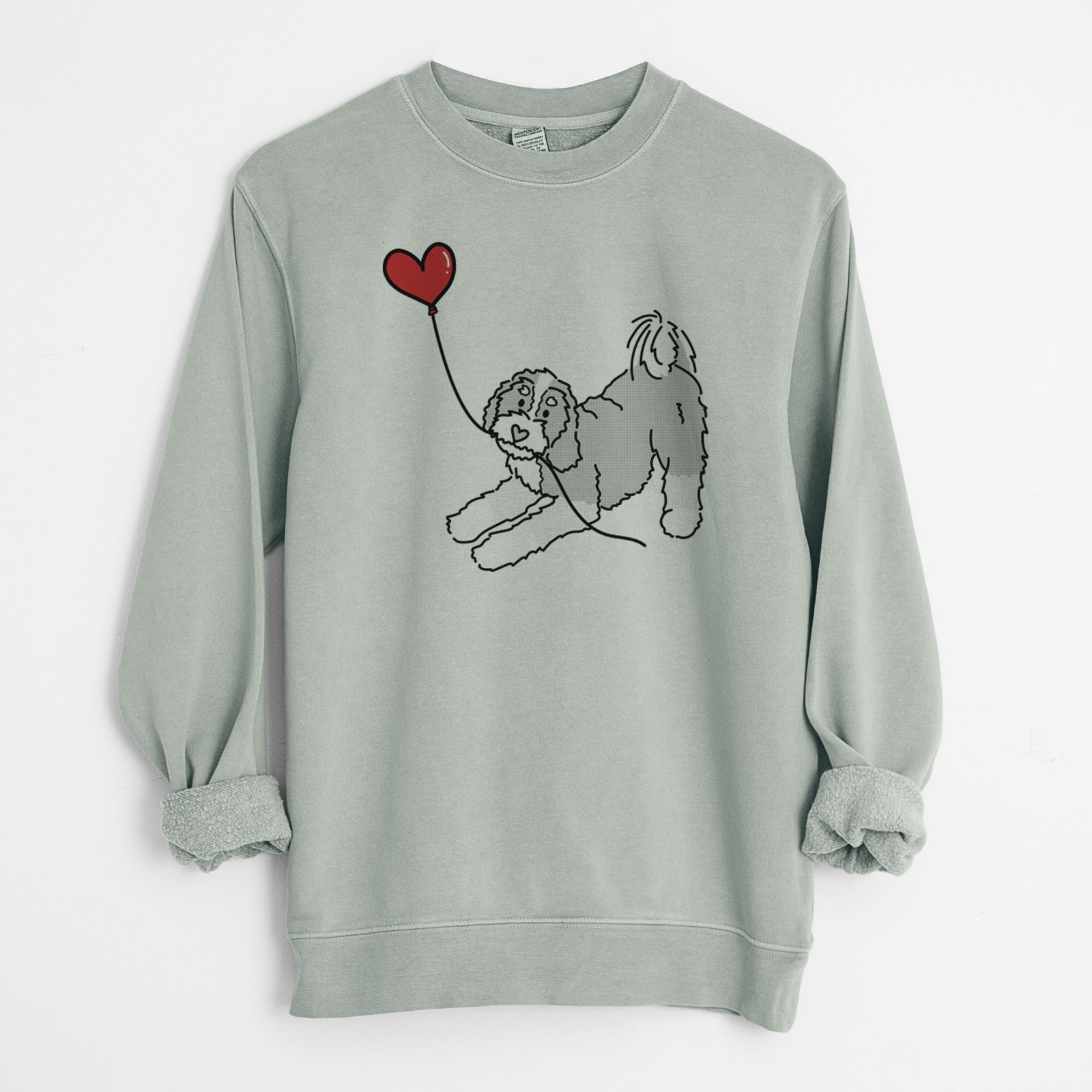Minimalist line drawing of a Bernedoodle Heart String holding a heart balloon on a Sage Unisex pigment dyed crew sweatshirt