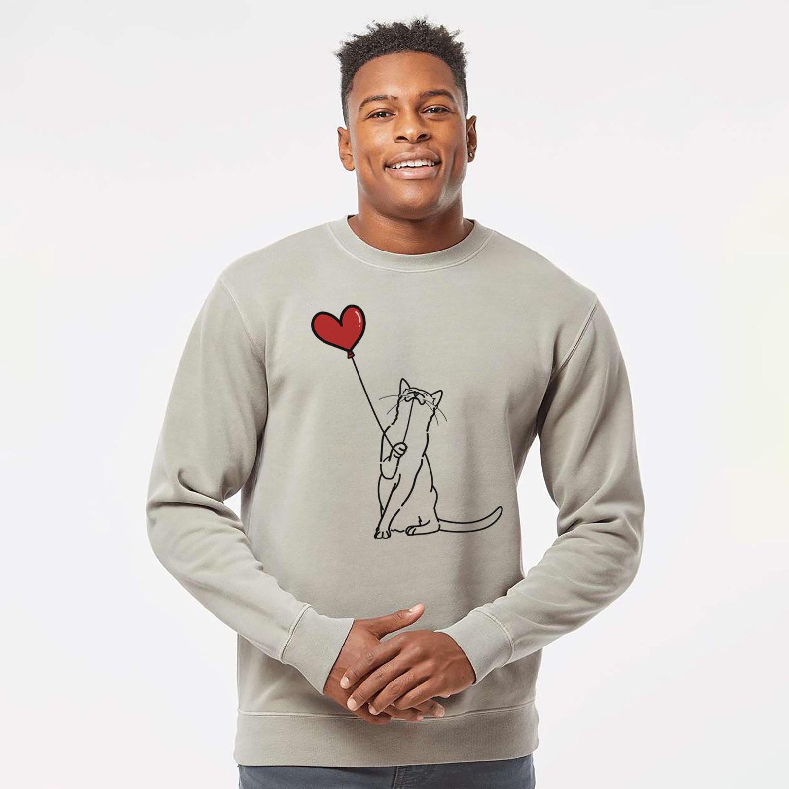 Minimalist line drawing of a Cat Heart String holding a heart balloon on a Cement Unisex pigment dyed crew sweatshirt