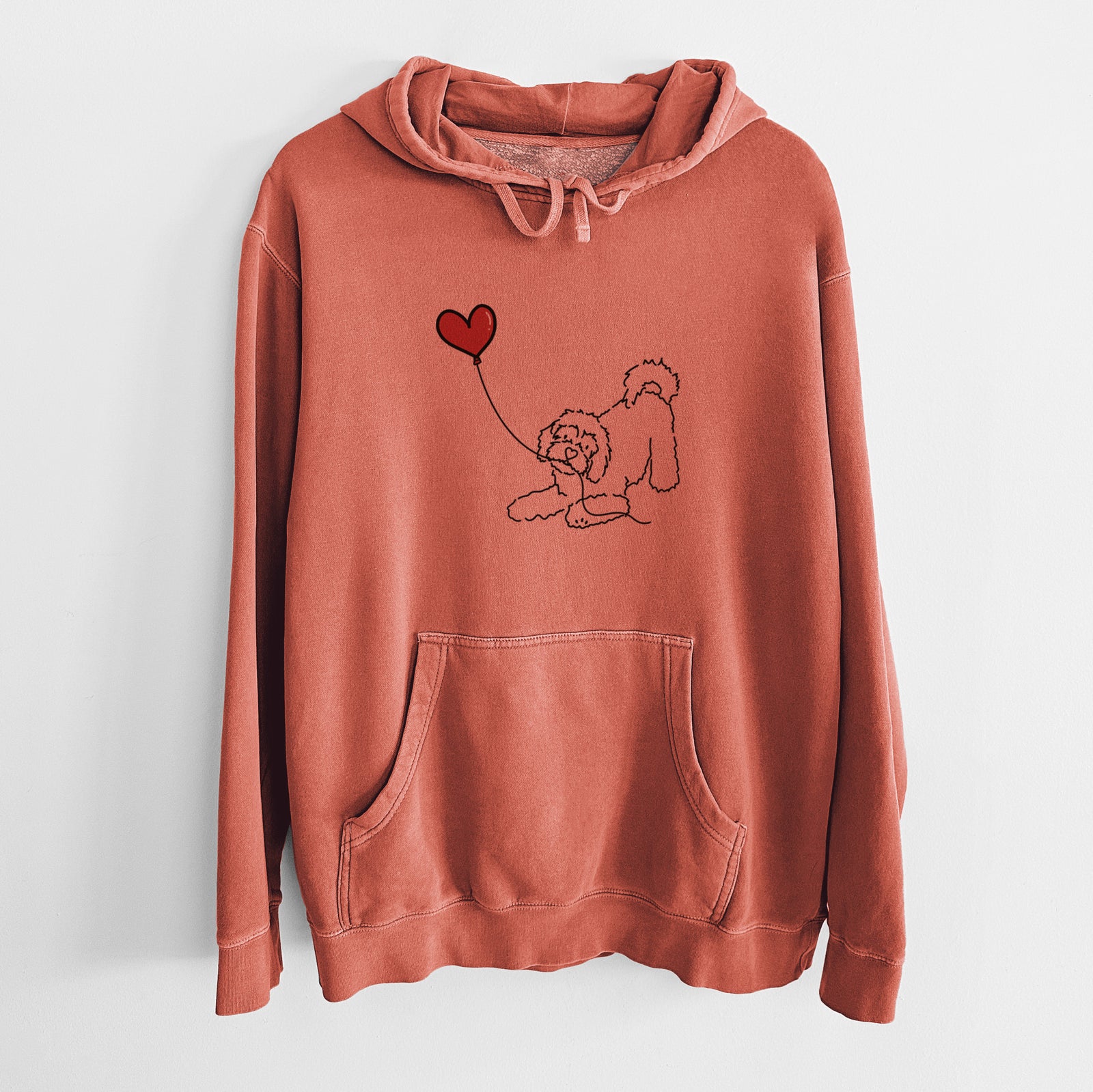 Minimalist line drawing of a Cavachon Heart String holding a heart balloon on an Amber Unisex pigment dyed hoodie
