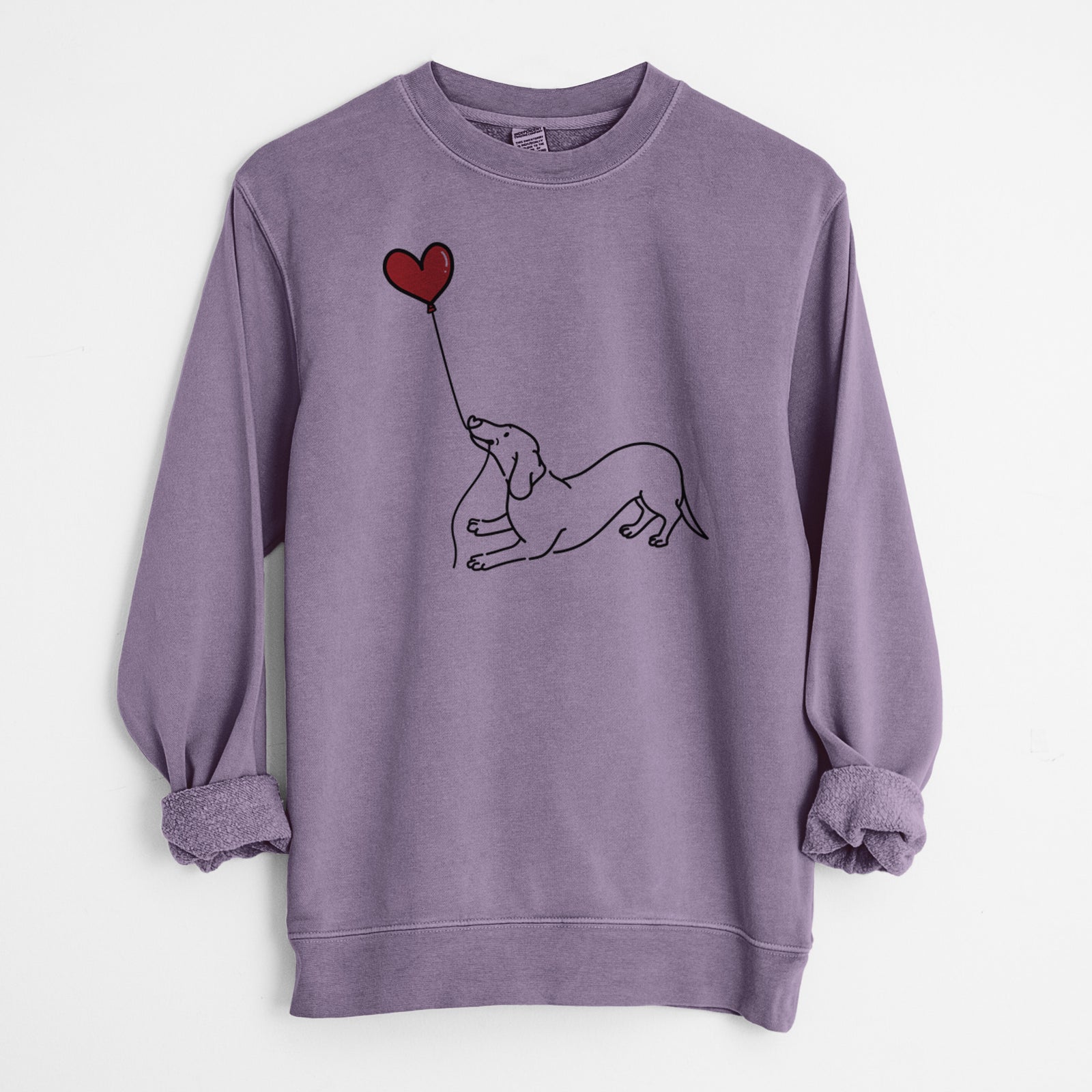 Minimalist line drawing of a Dachshund Heart String holding a heart balloon on a Plum Unisex pigment dyed crew sweatshirt