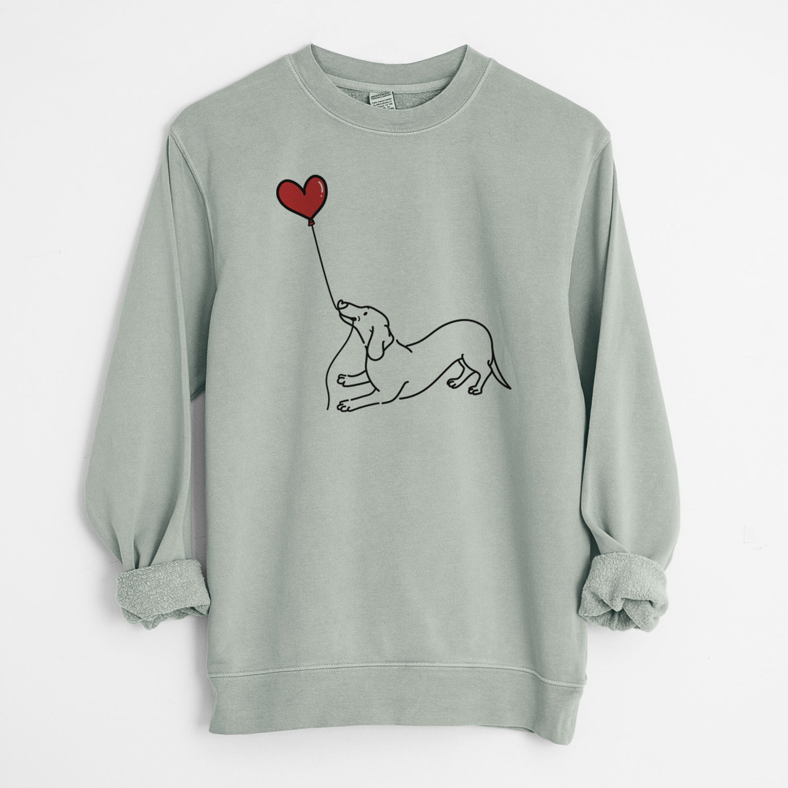 Minimalist line drawing of a Dachshund Heart String holding a heart balloon on a Sage Unisex pigment dyed crew sweatshirt