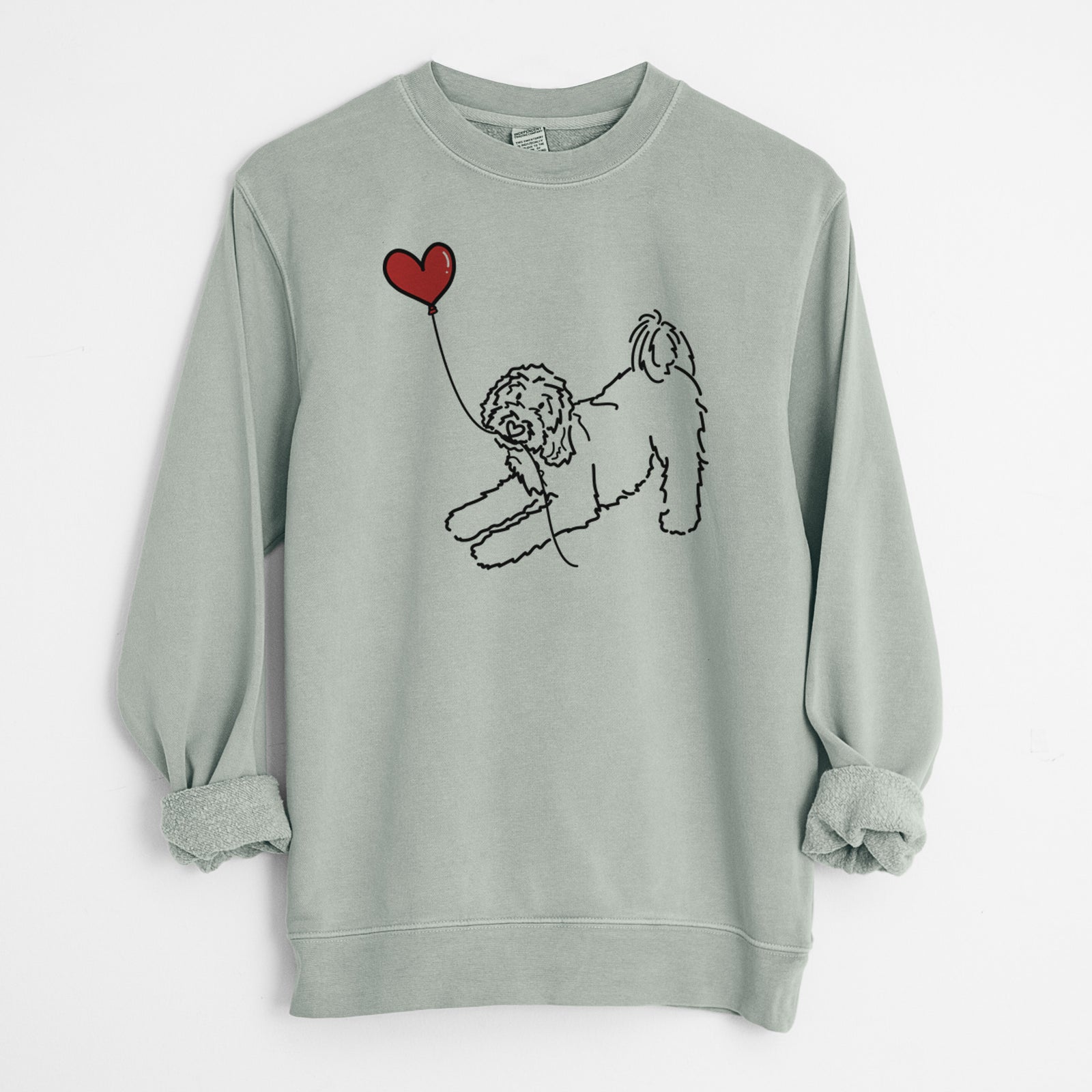 Minimalist line drawing of a Goldendoodle Heart String holding a heart balloon on a Sage Unisex pigment dyed crew sweatshirt
