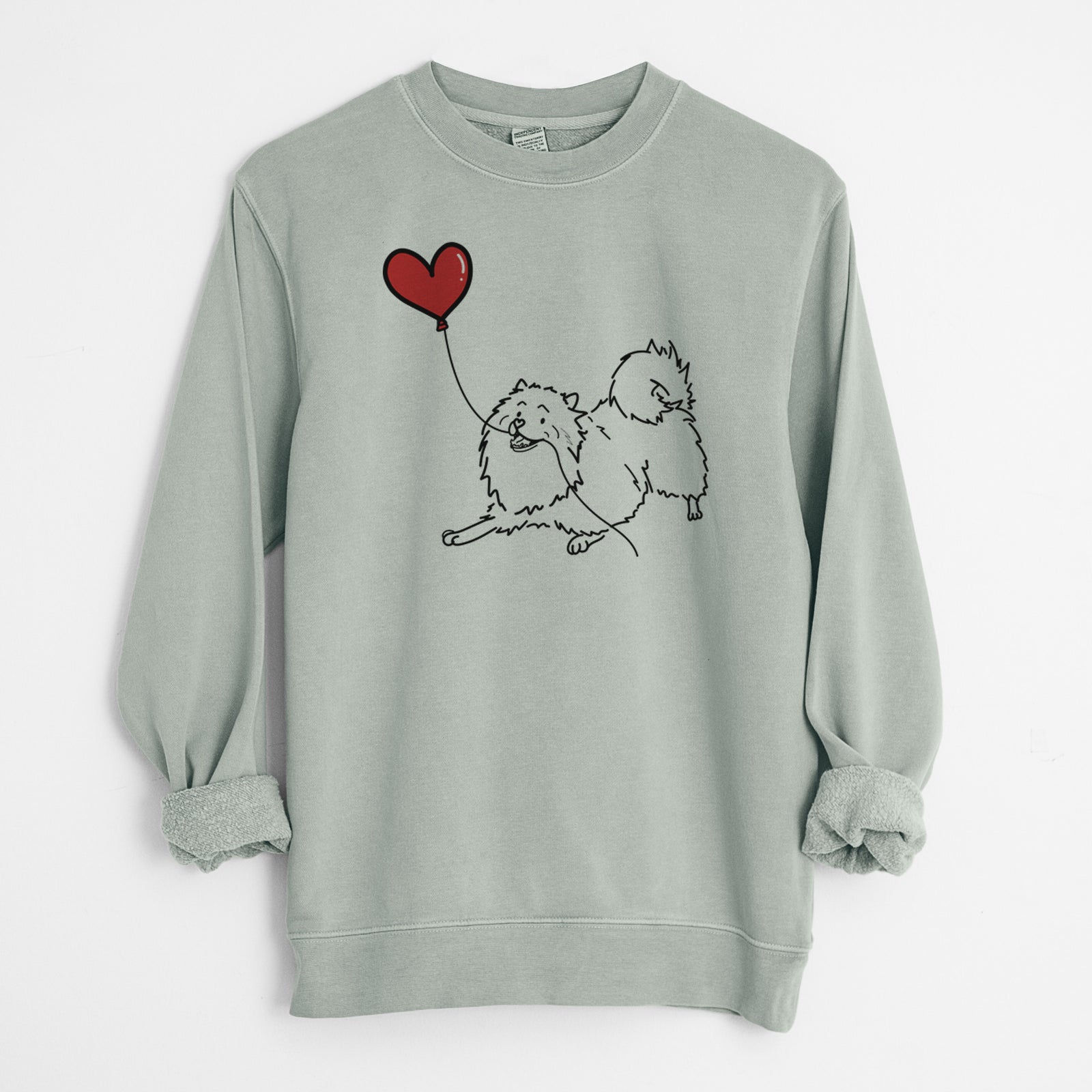 Minimalist line drawing of a Keeshond Heart String holding a heart balloon on a Sage Unisex pigment dyed crew sweatshirt
