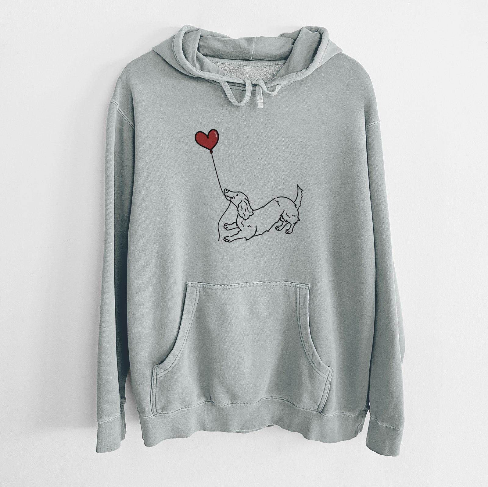 Minimalist line drawing of a Long Haired Dachshund Heart String holding a heart balloon on a Sage Unisex pigment dyed hoodie