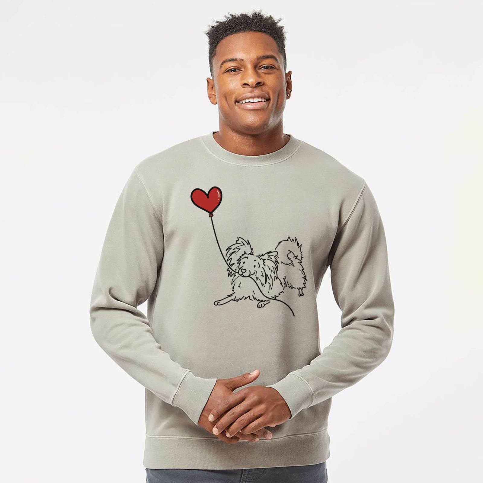 Minimalist line drawing of a Papillon Heart String holding a heart balloon on a Cement Unisex pigment dyed crew sweatshirt