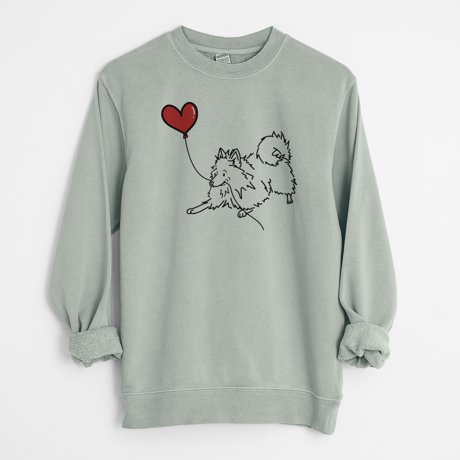 Minimalist line drawing of a Pomeranian Heart String holding a heart balloon on a Sage Unisex pigment dyed crew sweatshirt