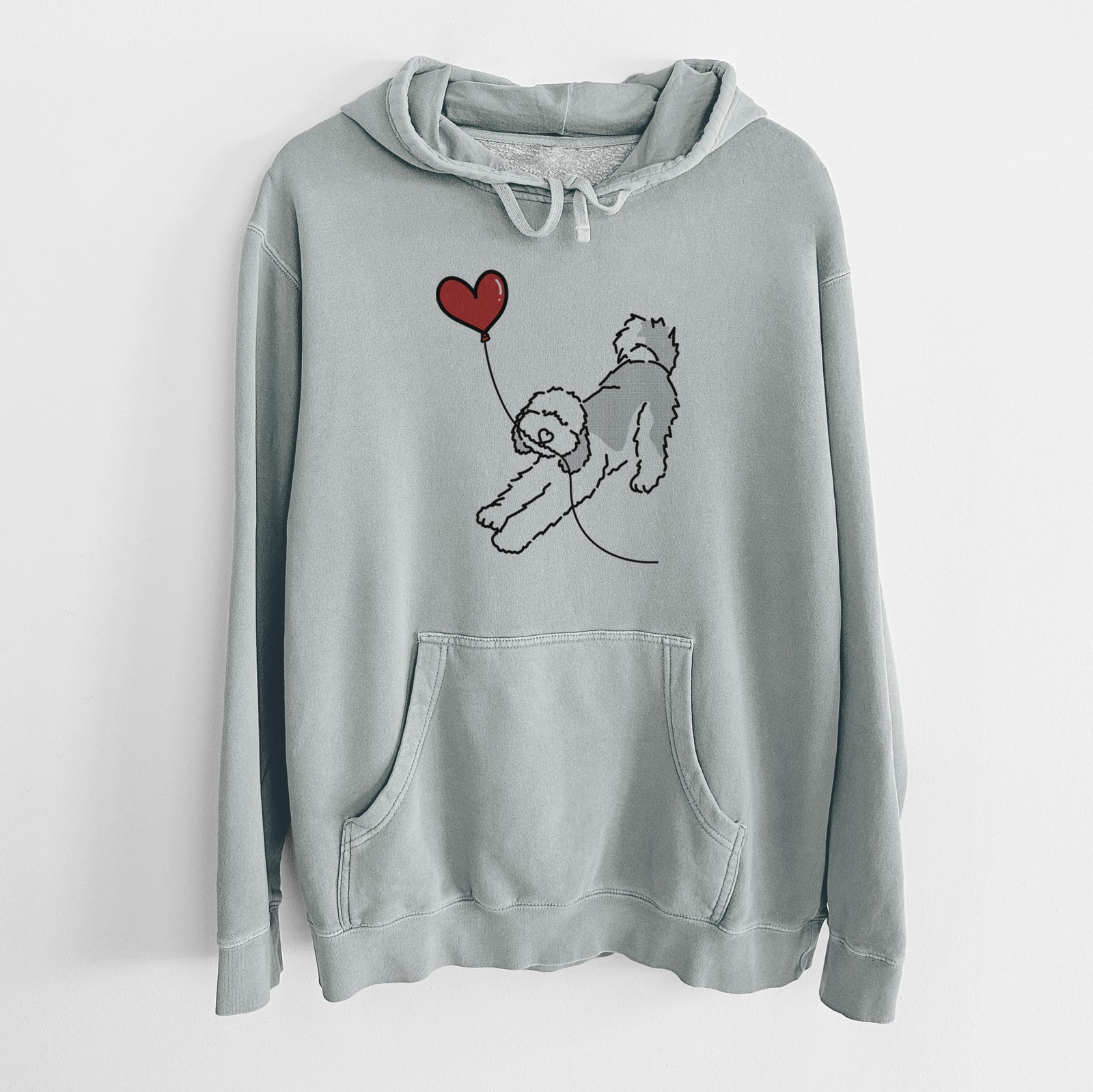Minimalist line drawing of a Sheepadoodle Heart String holding a heart balloon on a Sage Unisex pigment dyed hoodie