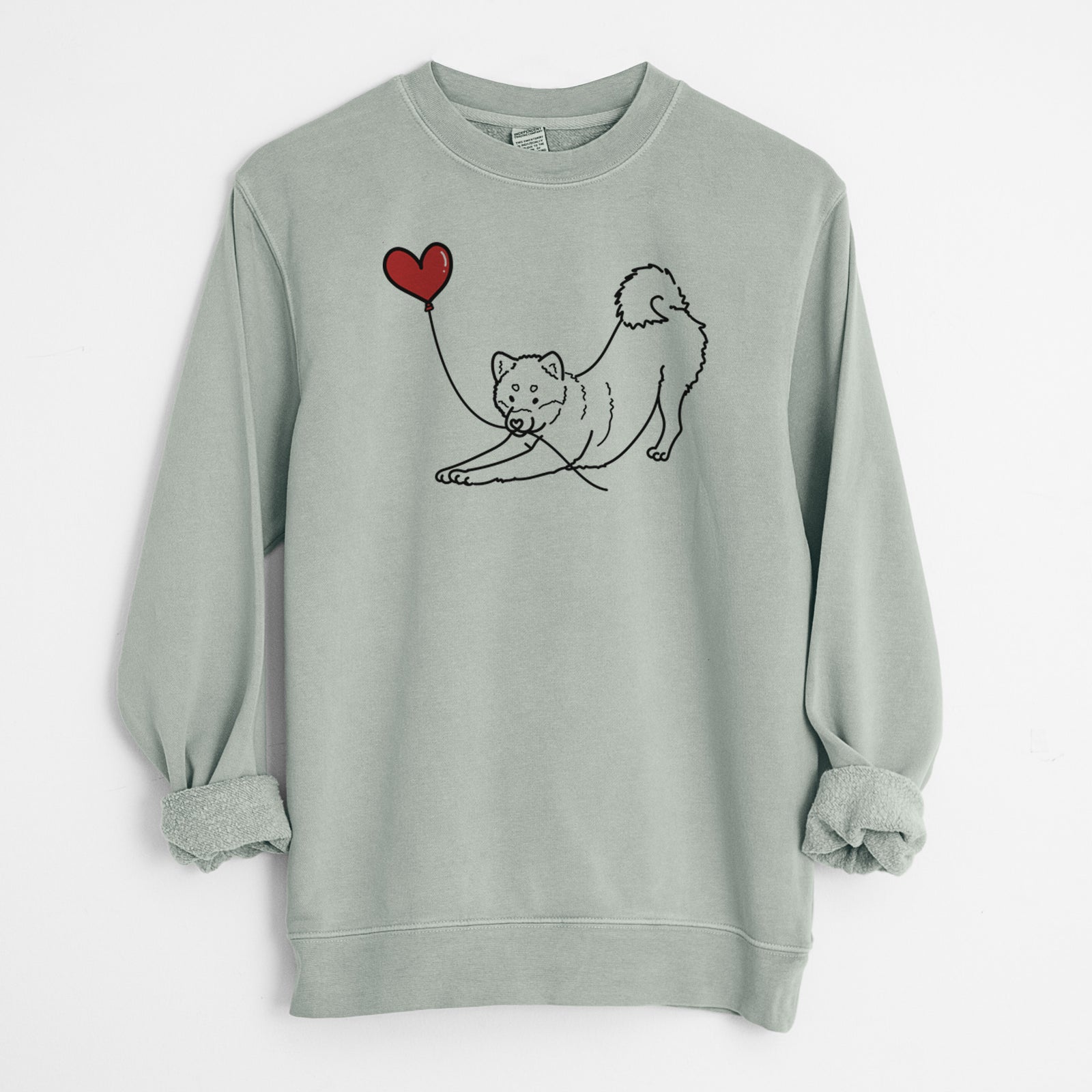 Minimalist line drawing of a Shiba Inu Heart String holding a heart balloon on a Sage Unisex pigment dyed crew sweatshirt