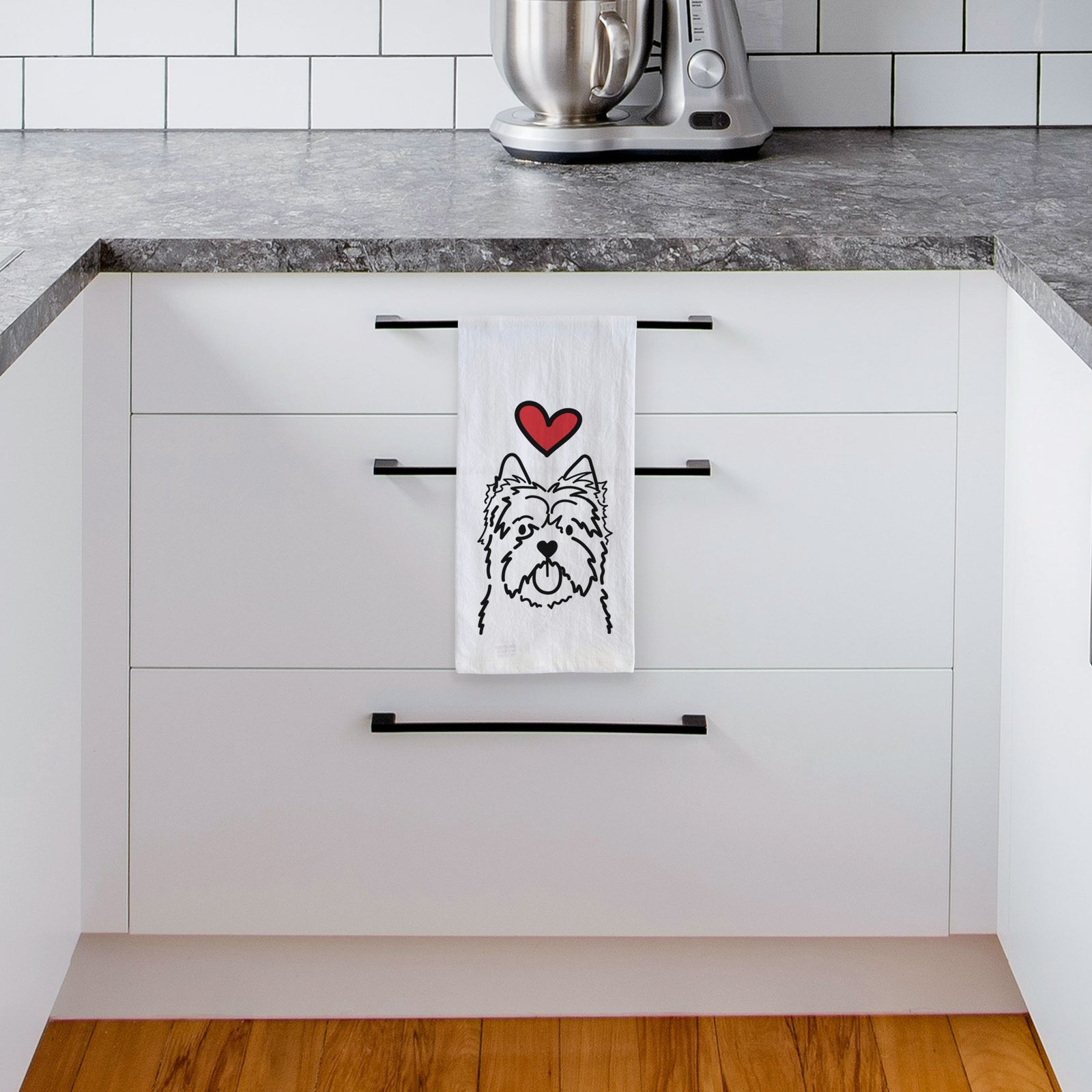 Minimalist line drawing of a Cairn Terrier with a red heart on a tea towel, hanging on an oven door in a kitchen