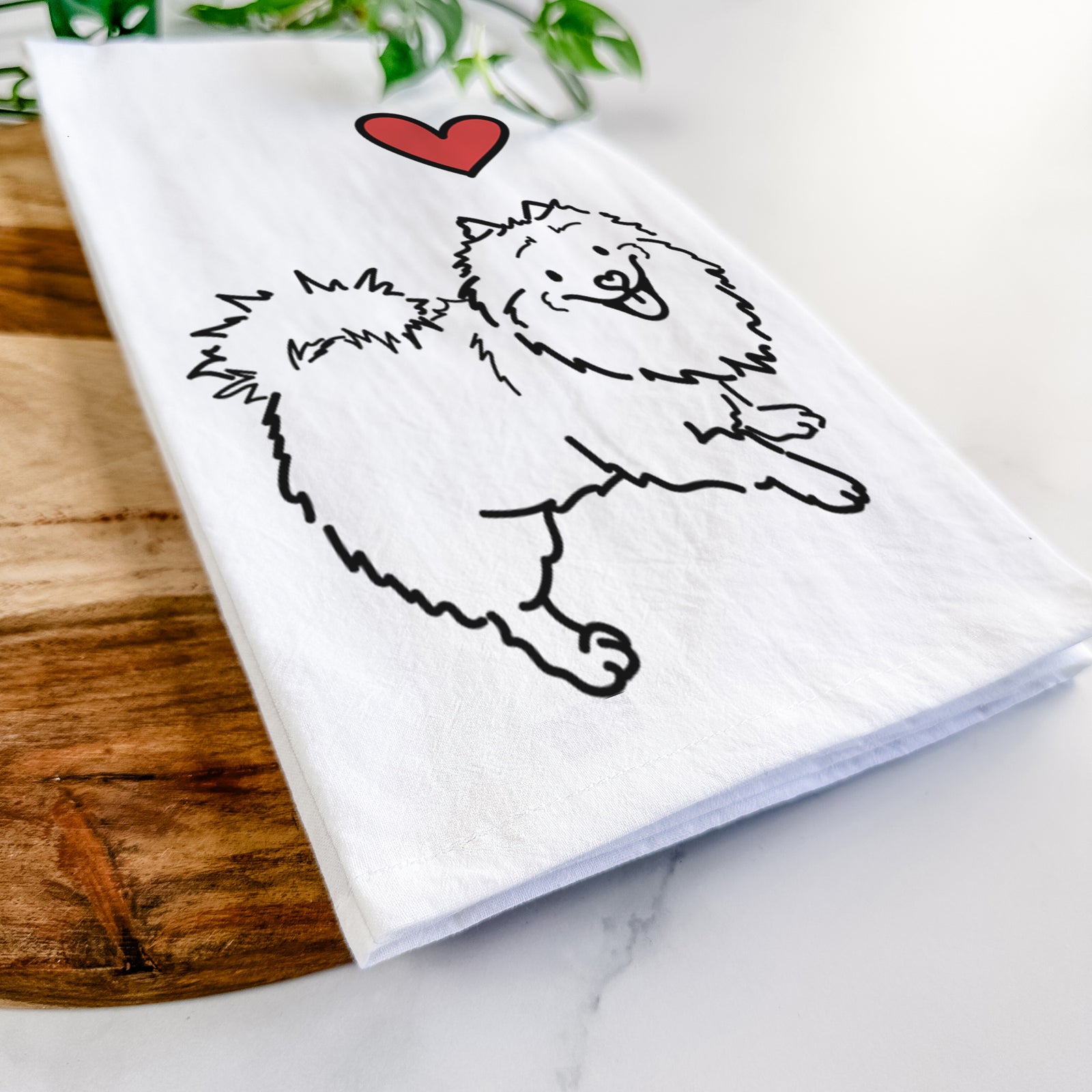 Minimalist line drawing of Goldie the Pomeranian Mix with a red heart on a tea towel
