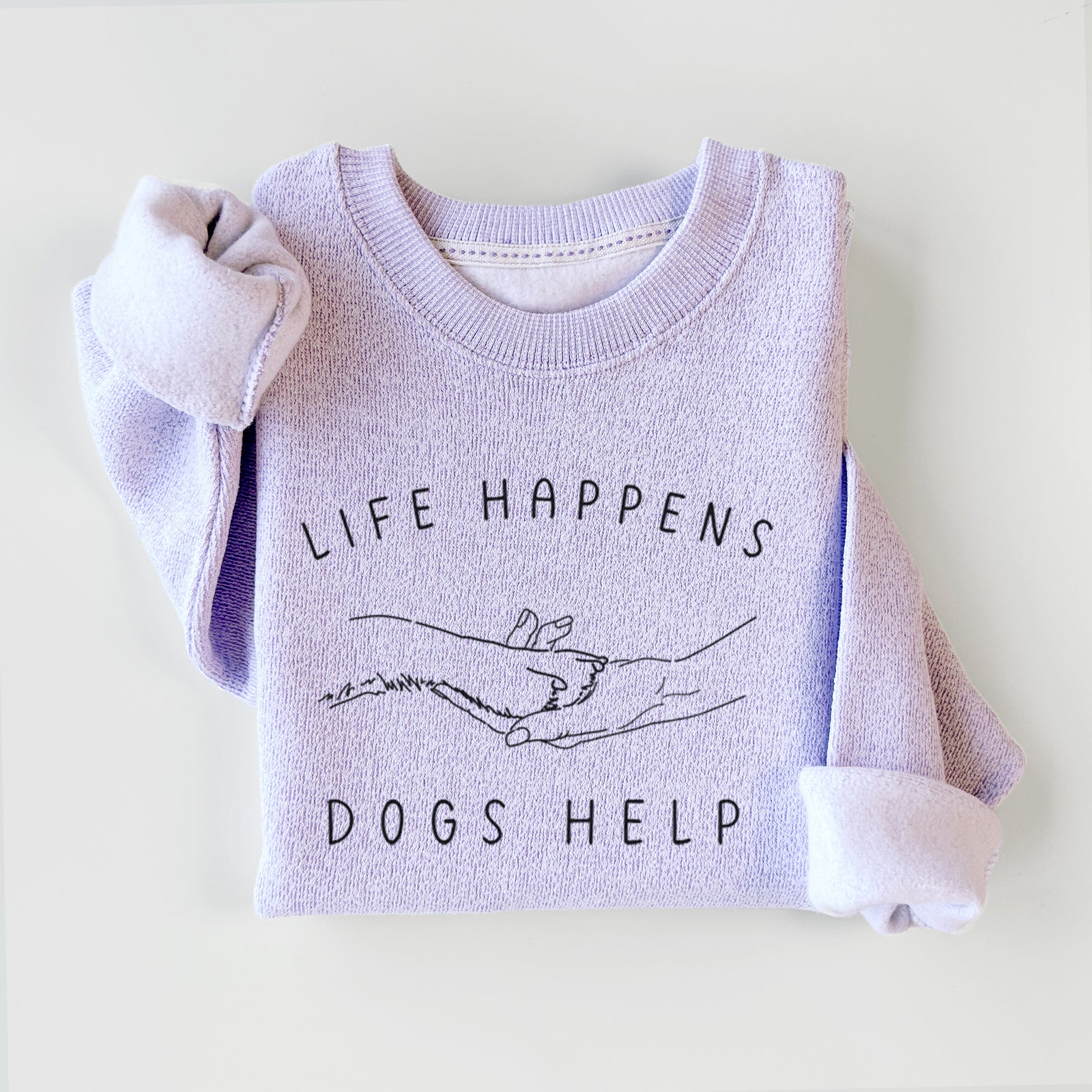 Folded sweater with 'Life Happens, Dogs Help' text on a light background