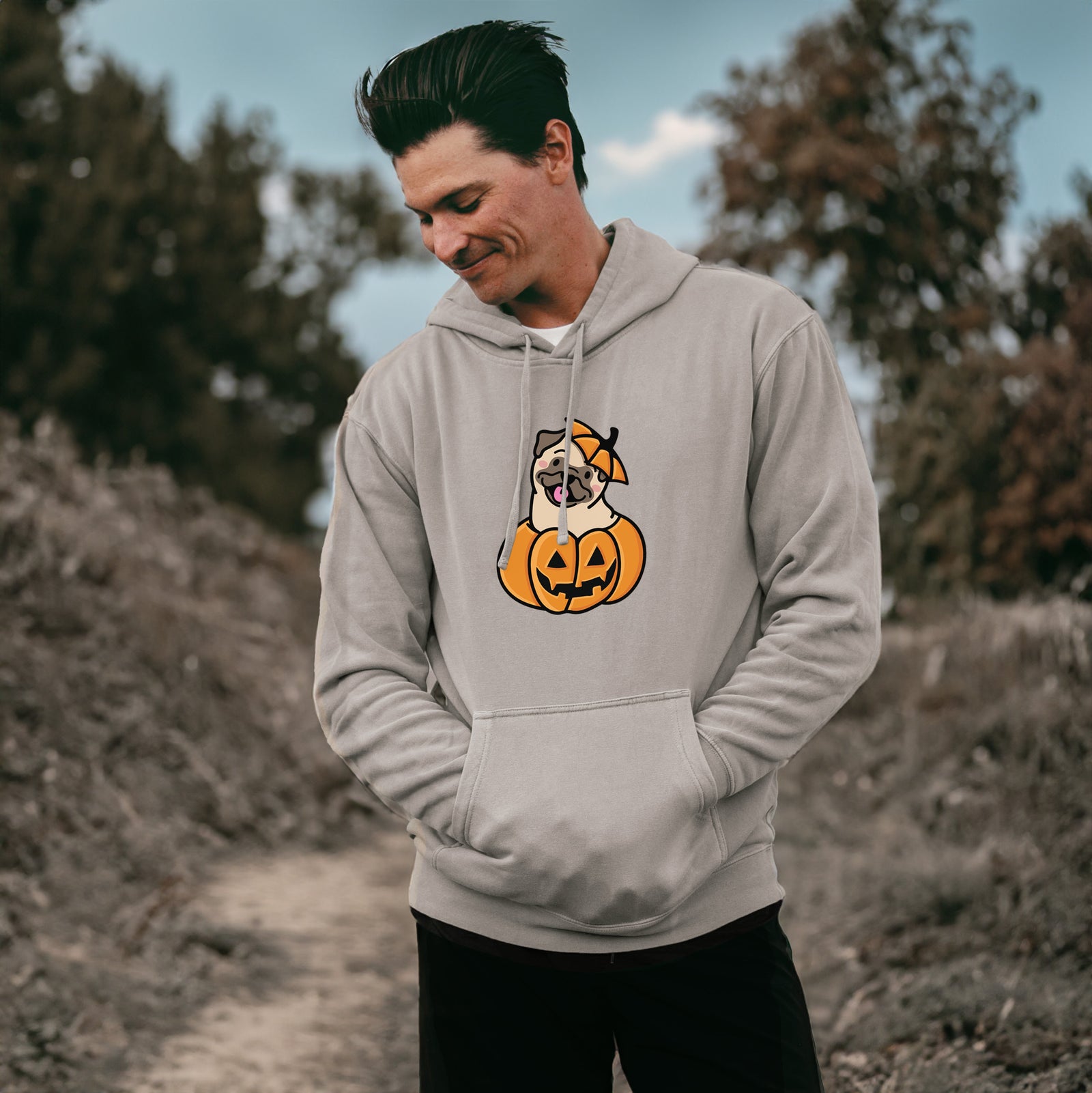 'Pumpkin Pup - Pug' design on a Cement Unisex pigment dyed hoodie, worn by a man