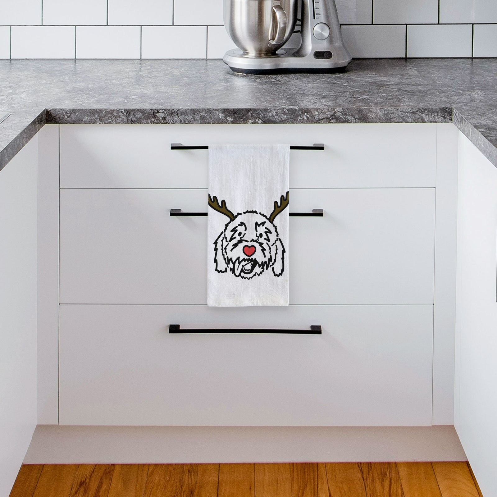 Minimalist line drawing of Barry the Goldendoodle with reindeer antlers and a red nose on a tea towel, hanging on an oven door in a kitchen
