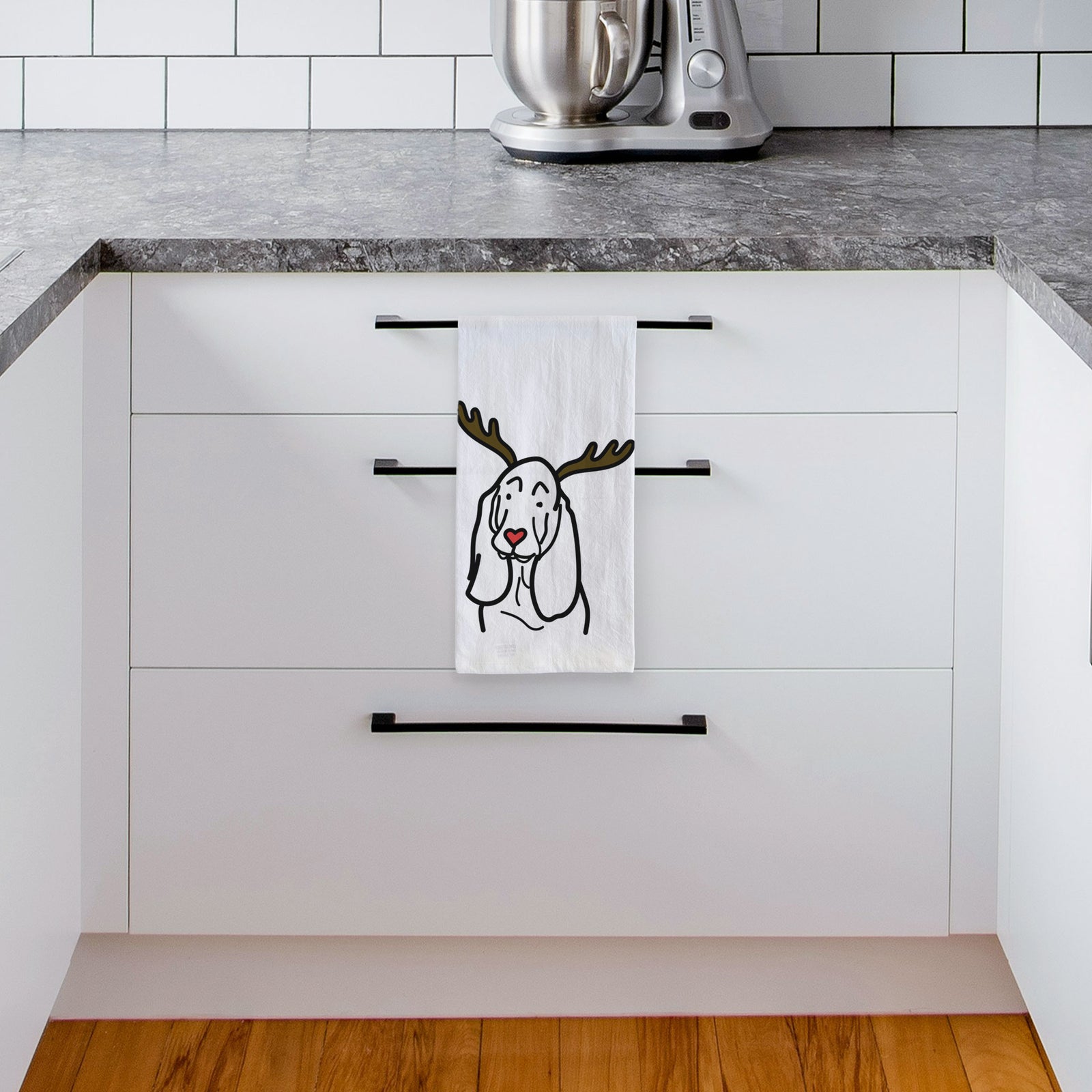Minimalist line drawing of a Basset Hound with reindeer antlers and a red nose on a tea towel, hanging on an oven door in a kitchen