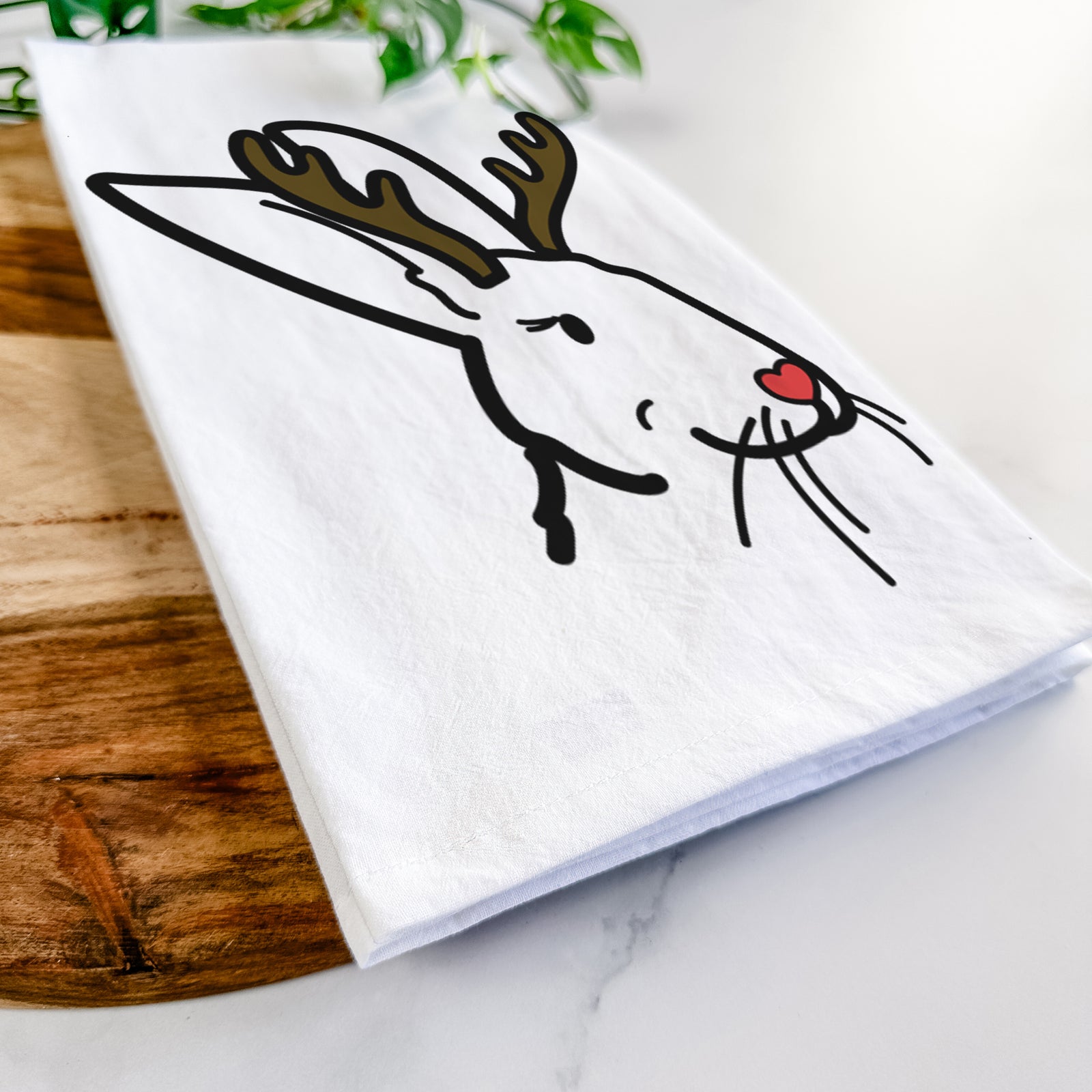 Minimalist line drawing of Betsy the Rex Rabbit with reindeer antlers and a red nose on a tea towel