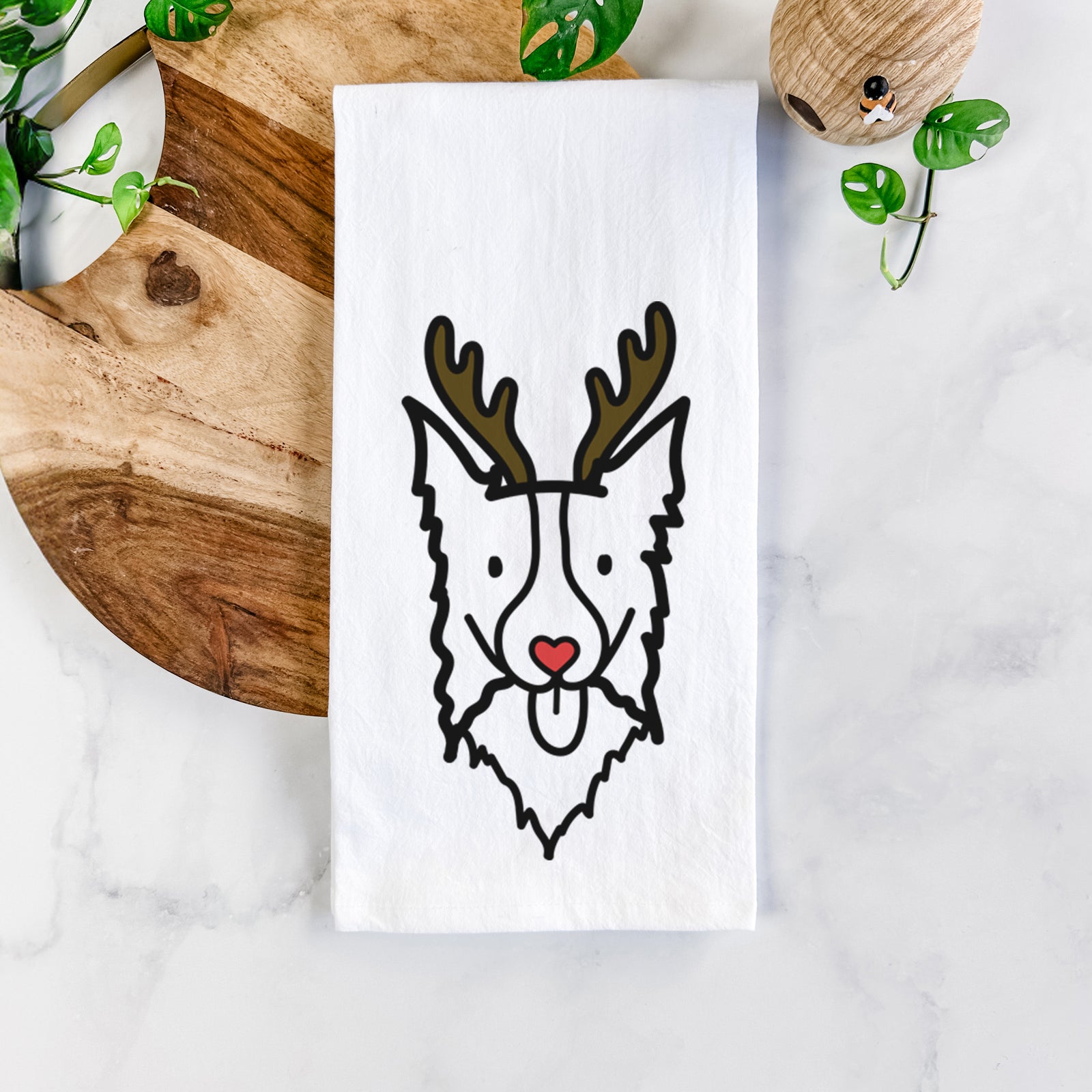 Minimalist line drawing of a Border Collie with reindeer antlers and a red nose on a tea towel