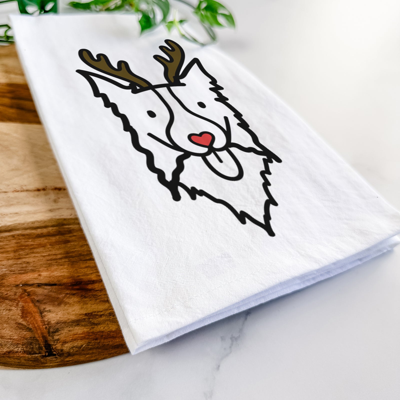 Minimalist line drawing of a Border Collie with reindeer antlers and a red nose on a tea towel