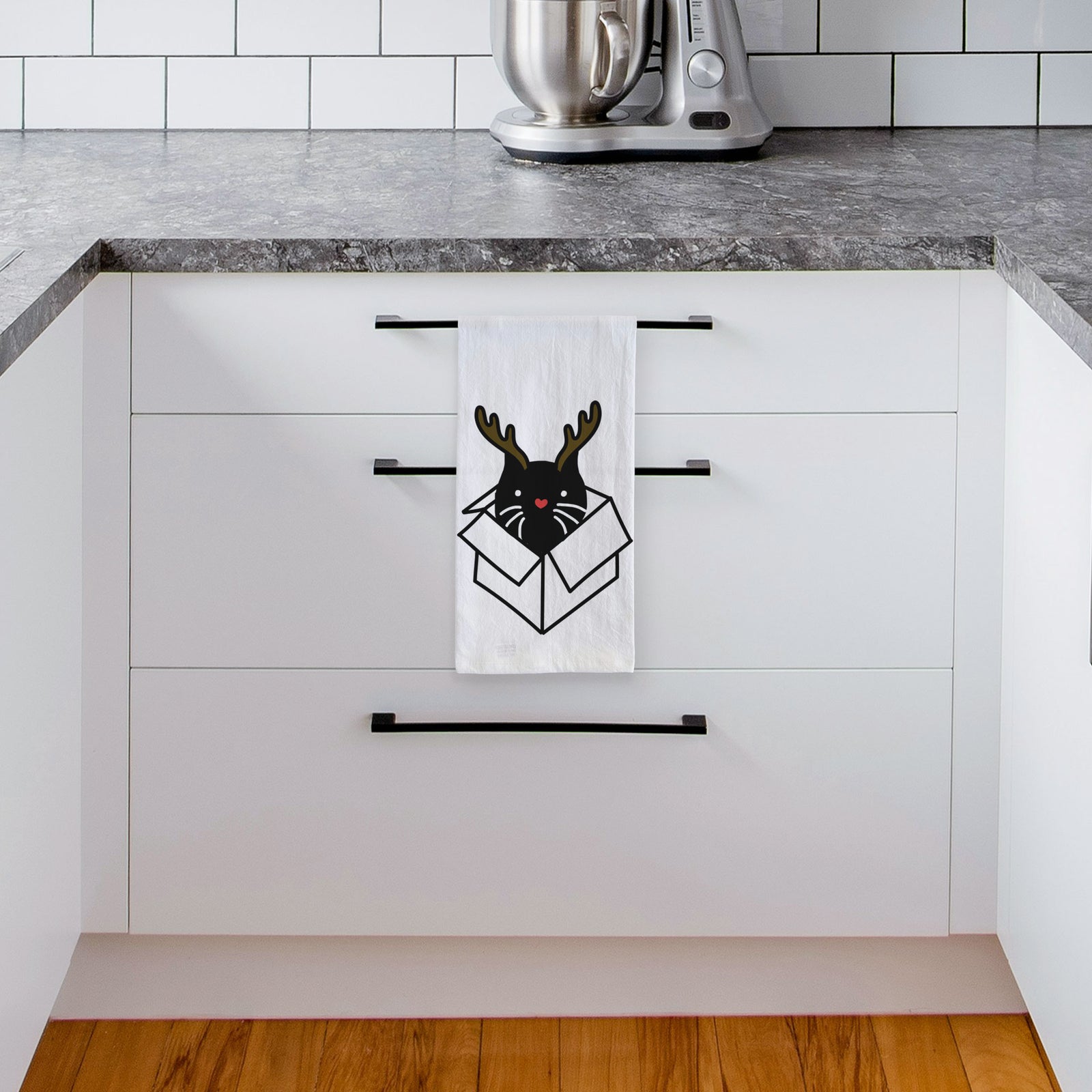 Minimalist line drawing of Doc the Black Cat in a Box with reindeer antlers and a red nose on a tea towel, hanging on an oven door in a kitchen
