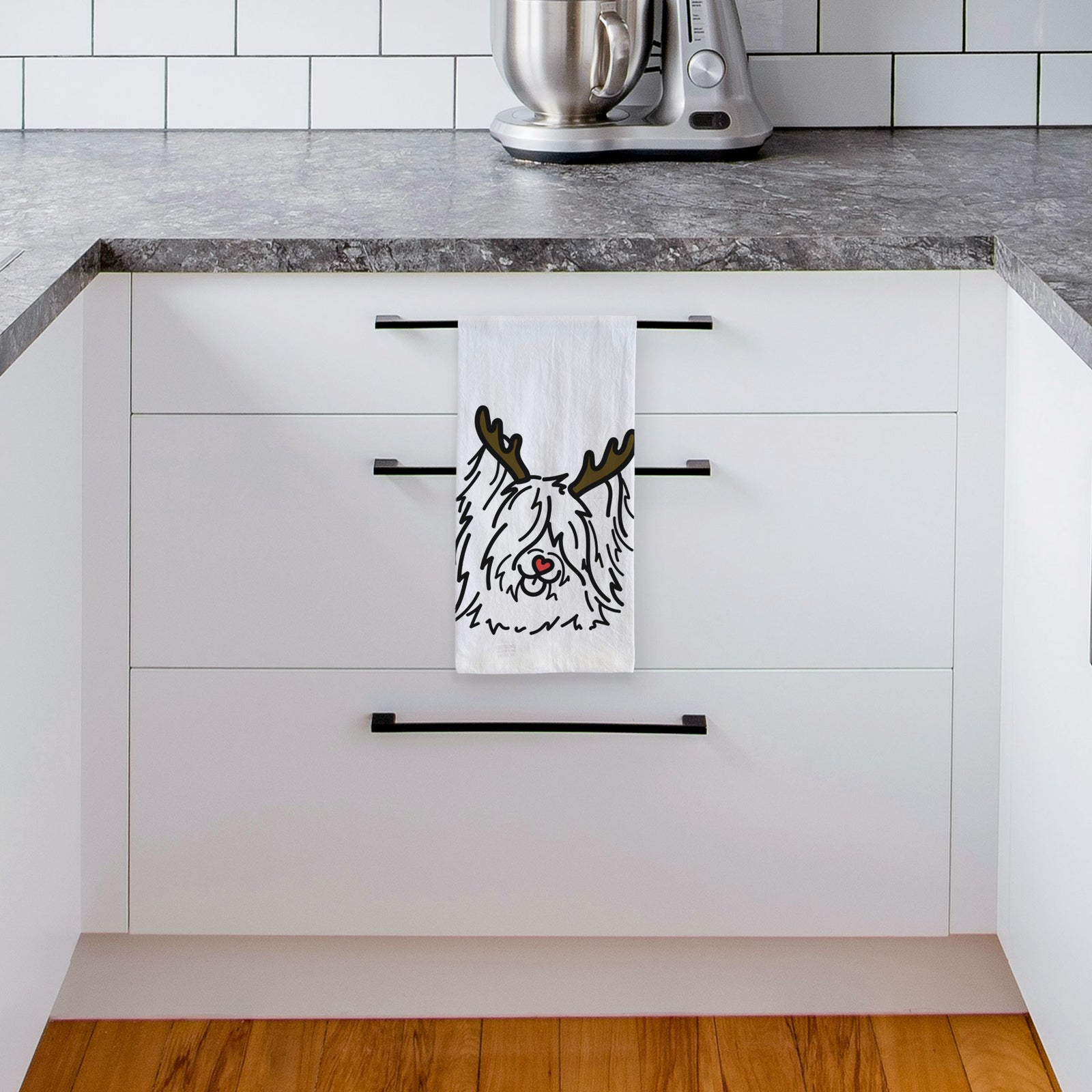 Minimalist line drawing of Dougal the Skye Terrier with reindeer antlers and a red nose on a tea towel, hanging on an oven door in a kitchen