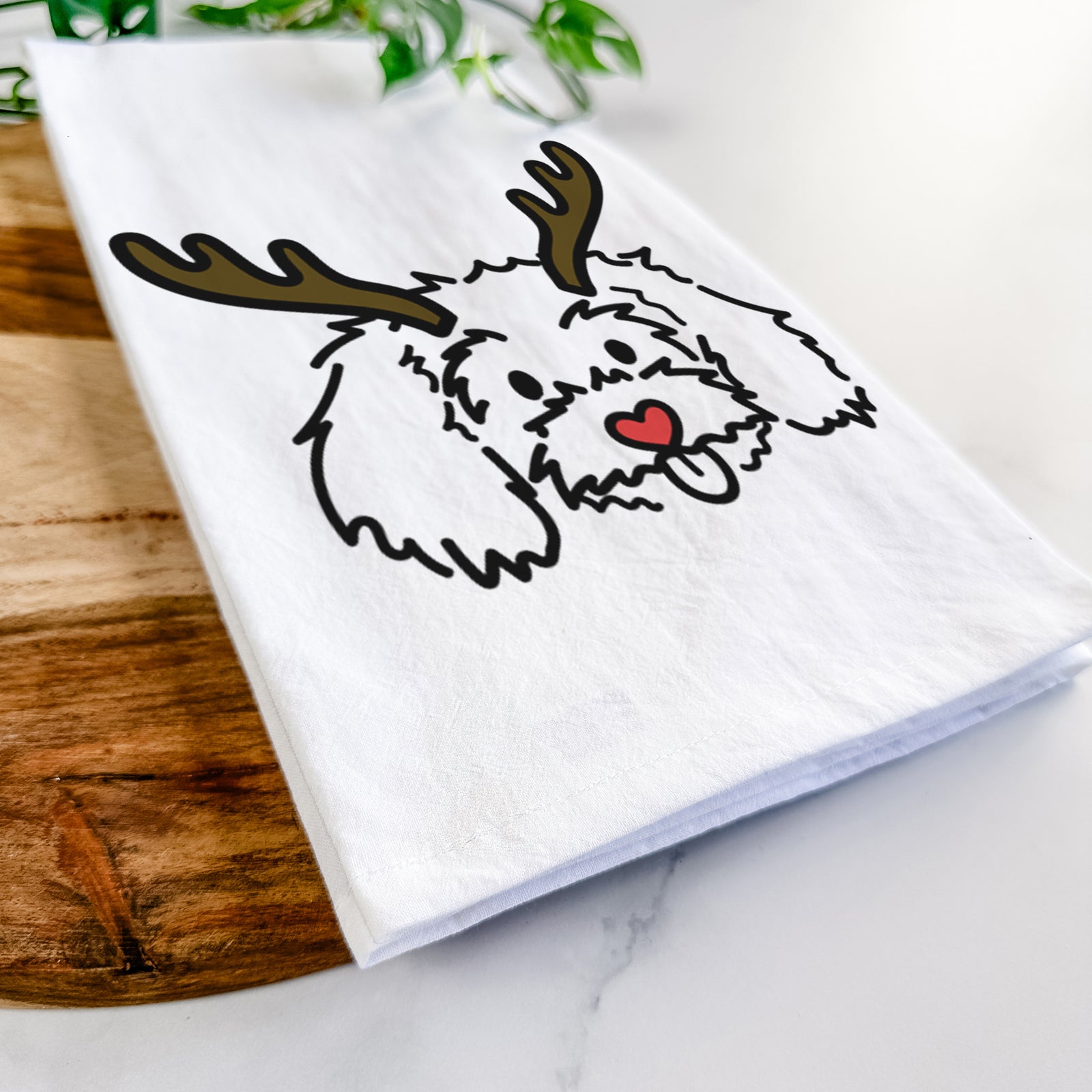 Minimalist line drawing of Holly the Maltipoo with reindeer antlers and a red nose on a tea towel