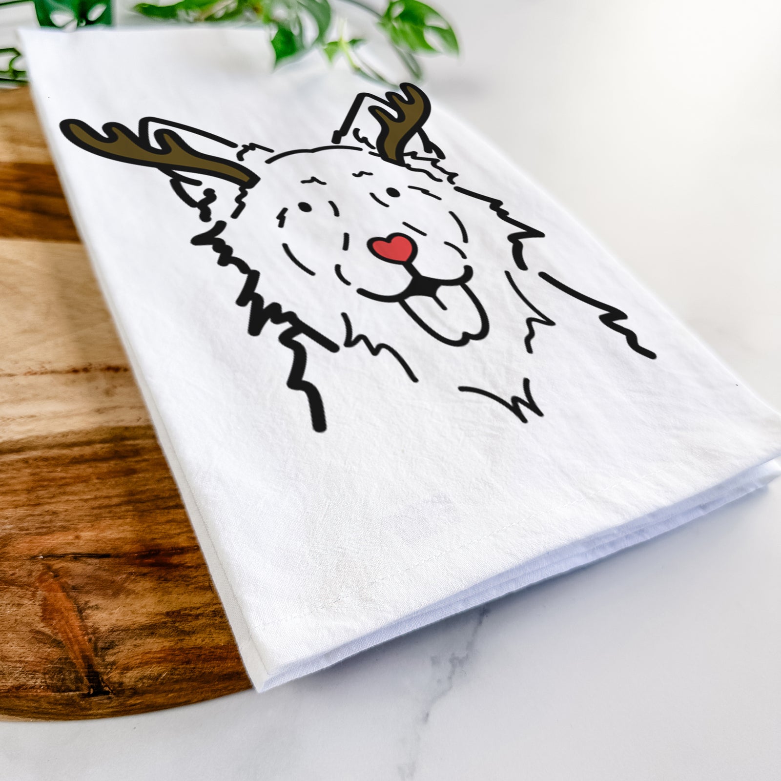 Minimalist line drawing of Jack the Mudi with reindeer antlers and a red nose on a tea towel