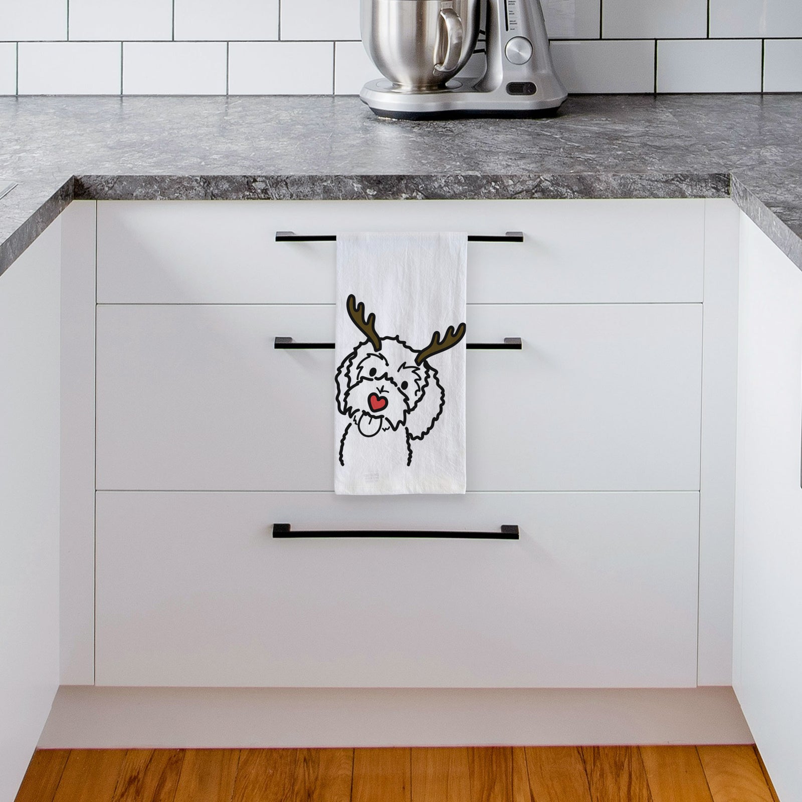 Minimalist line drawing of Mabel the Bernedoodle with reindeer antlers and a red nose on a tea towel, hanging on an oven door in a kitchen