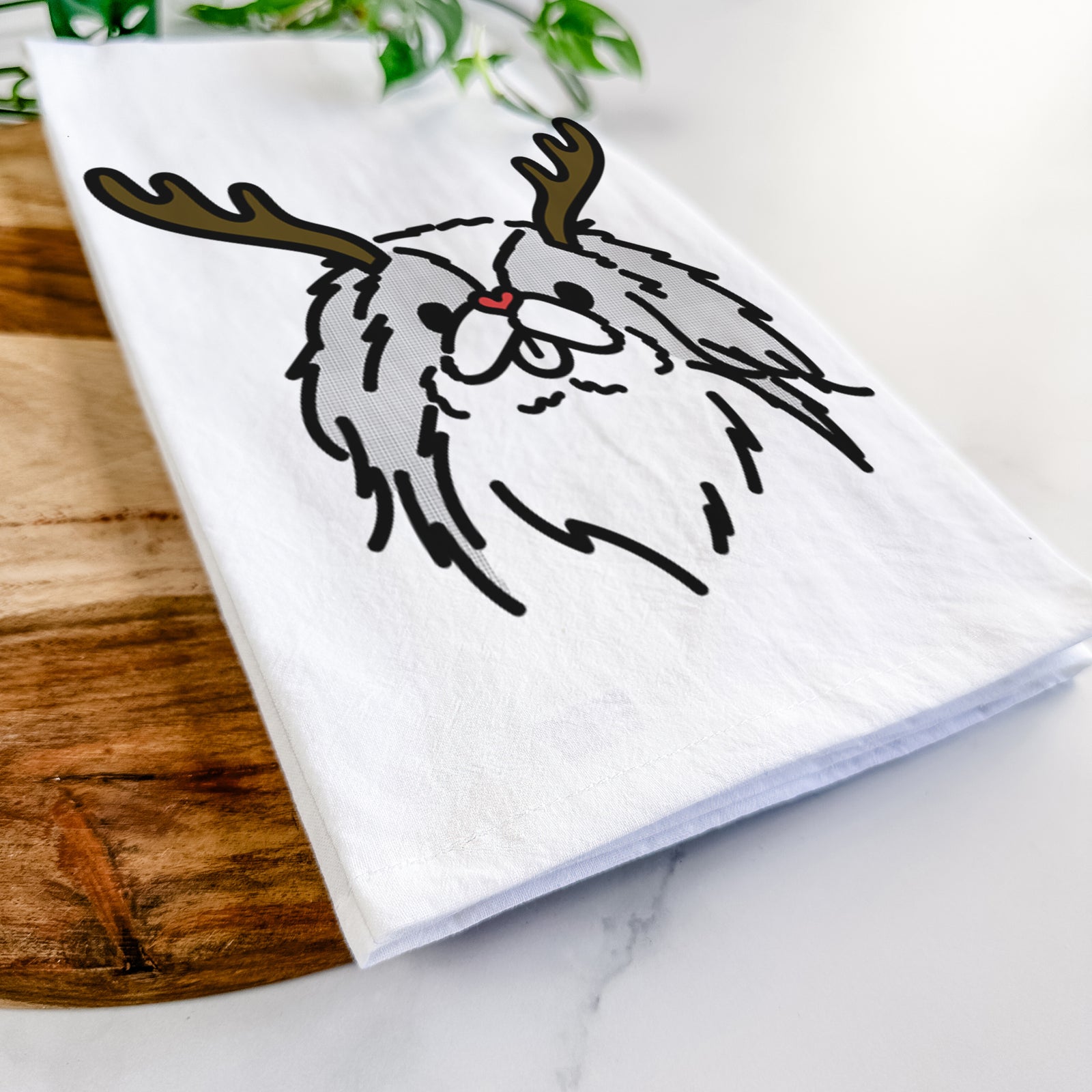 Minimalist line drawing of Macha the Japanese Chin with reindeer antlers and a red nose on a tea towel