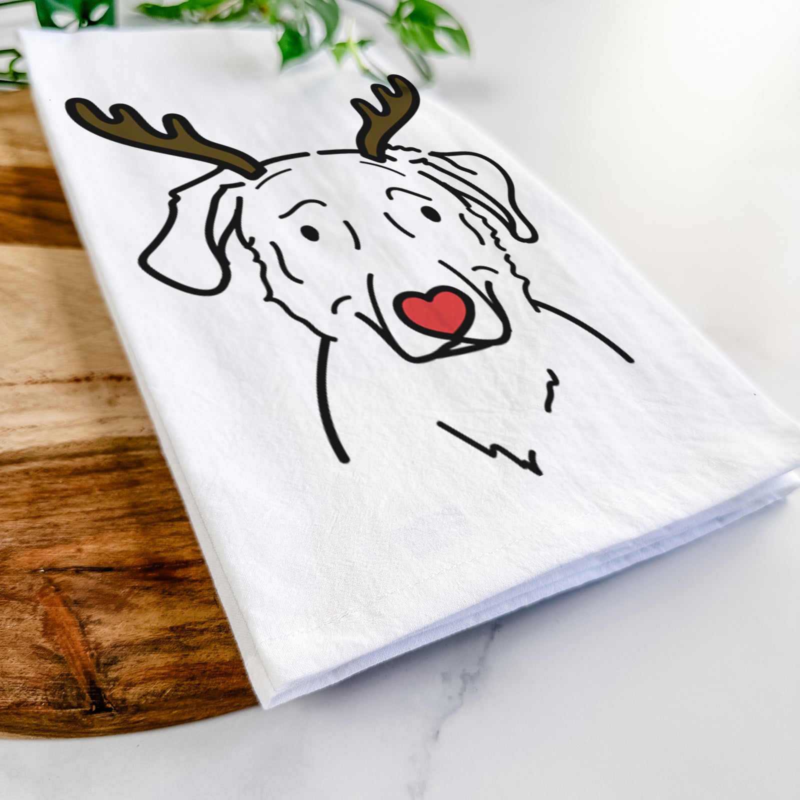 Minimalist line drawing of Mitzi the Golden Retriever Mix with reindeer antlers and a red nose on a tea towel