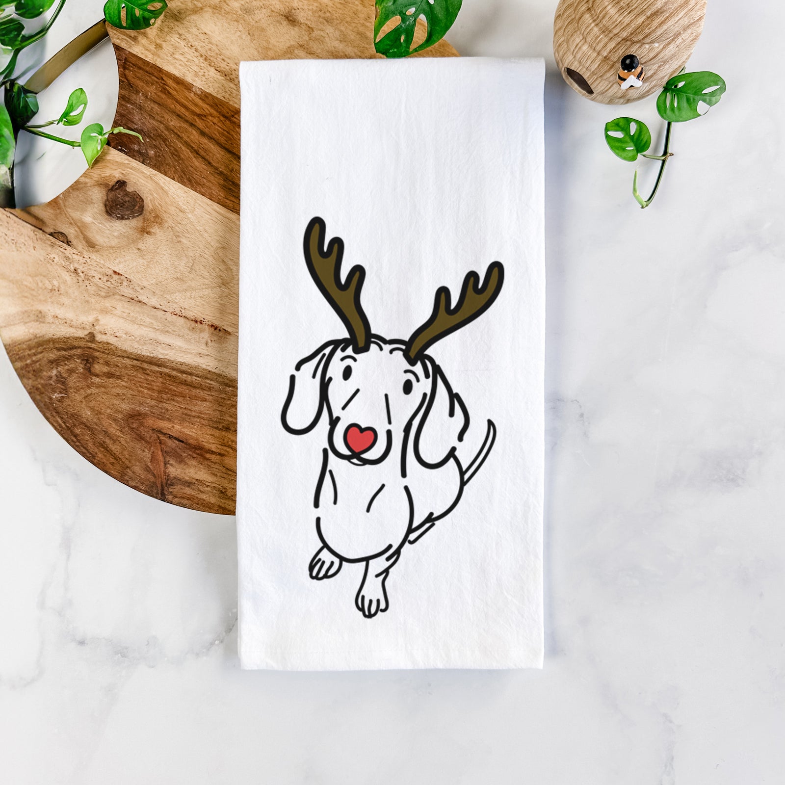 Minimalist line drawing of Moxie the Dachshund with reindeer antlers and a red nose on a tea towel
