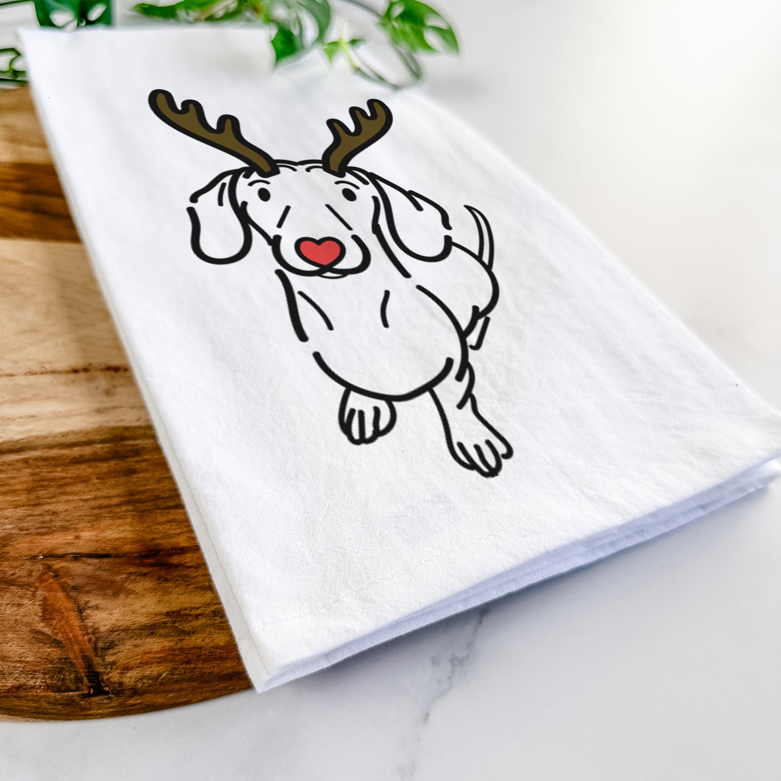 Minimalist line drawing of Moxie the Dachshund with reindeer antlers and a red nose on a tea towel