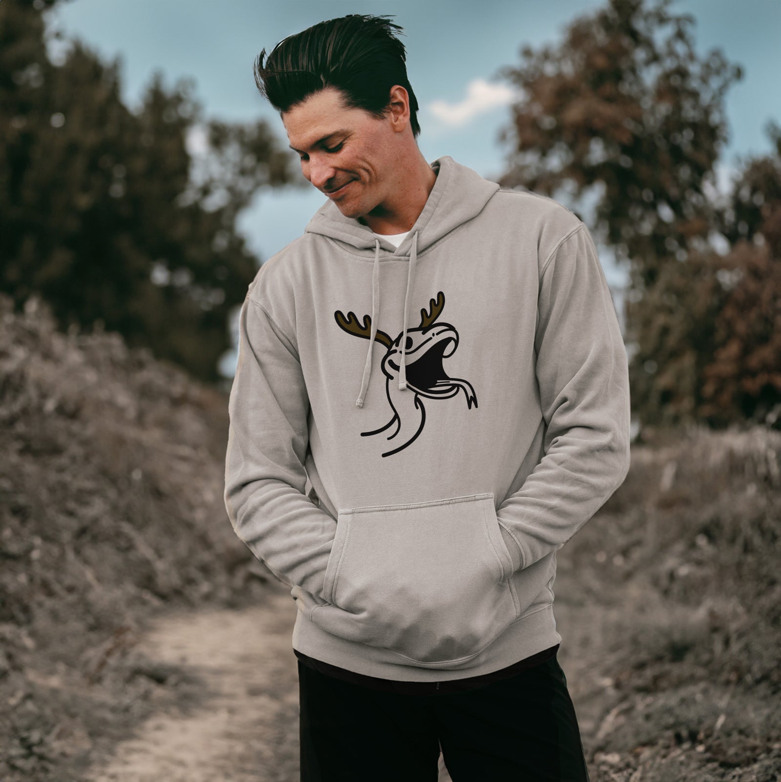 Minimalist line drawing of Spike the Snake with reindeer antlers and a red nose on a Cement Unisex pigment dyed hoodie, worn by a man