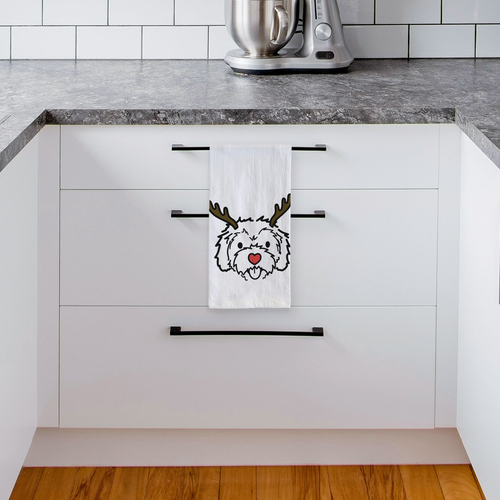 Minimalist line drawing of Sprinkles the Cockapoo with reindeer antlers and a red nose on a tea towel, hanging on an oven door in a kitchen
