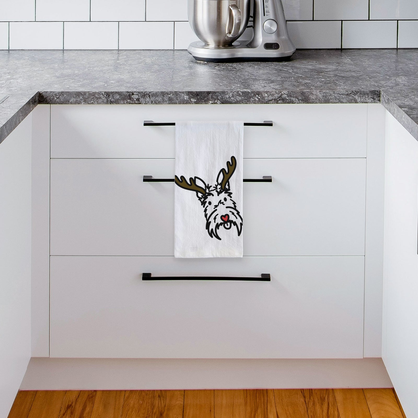 Minimalist line drawing of Thistle the Scottish Terrier with reindeer antlers and a red nose on a tea towel, hanging on an oven door in a kitchen